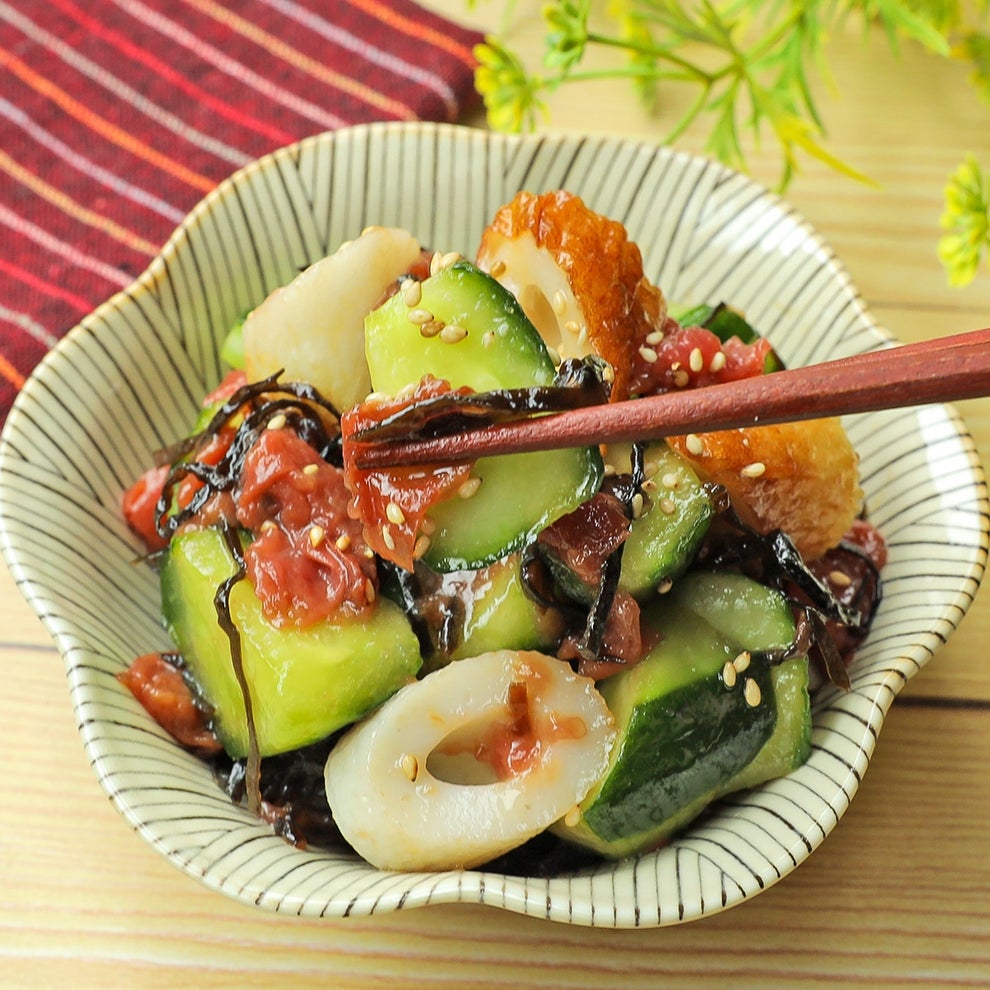 きゅうりとちくわの和風サラダ、梅干しや昆布、胡麻が添えられた料理を箸で食べる様子。