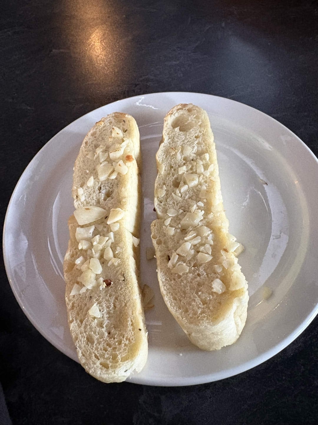 Two slices of bread topped with chopped garlic on a white plate