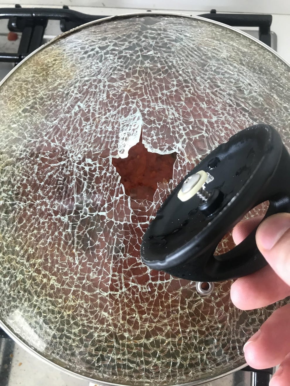 Cracked glass pot lid with a handle detached; a leaf-shaped section is missing from the glass