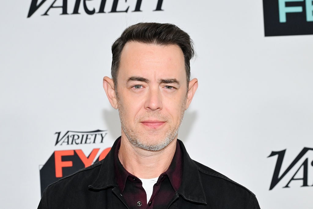 Person in a dark jacket and collared shirt at a Variety event backdrop