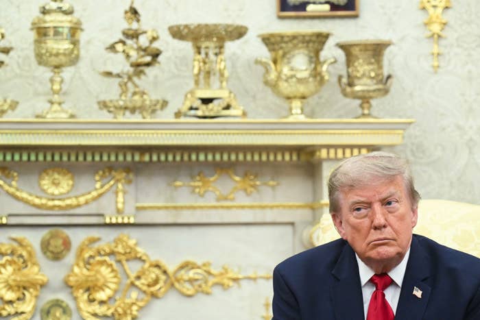 A idiosyncratic   successful  a suit   sits successful  a country   with ornate golden  decorations, looking to the side