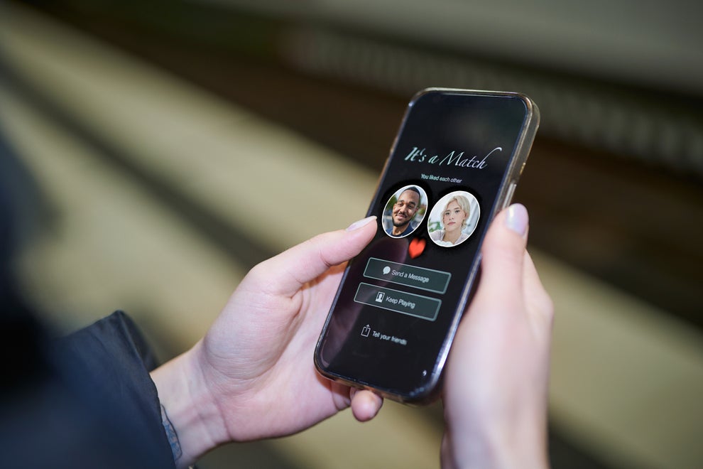 Person holding a phone displaying a dating app screen with "It's a Match!" and options to message or keep playing