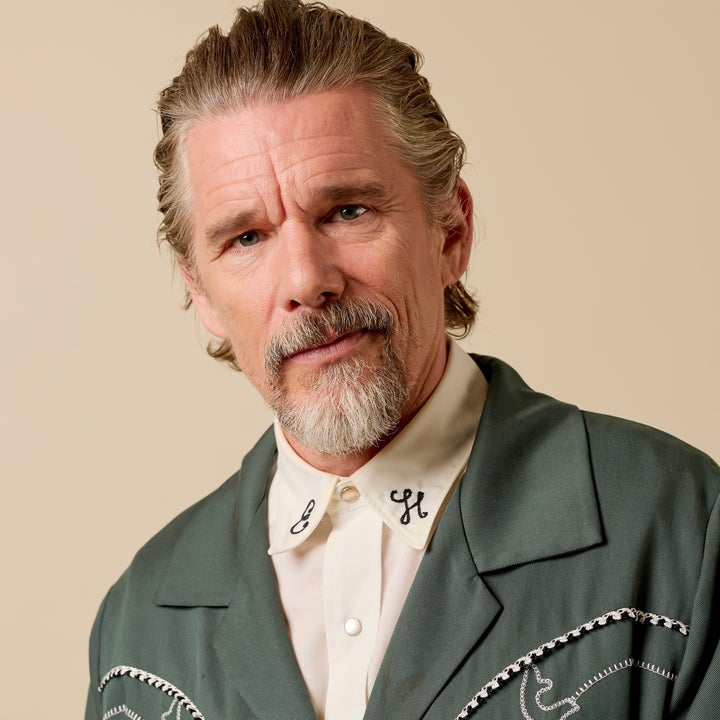 Ethan Hawke with a short beard and slicked-back hair wearing a stylish jacket and shirt with decorative embroidery
