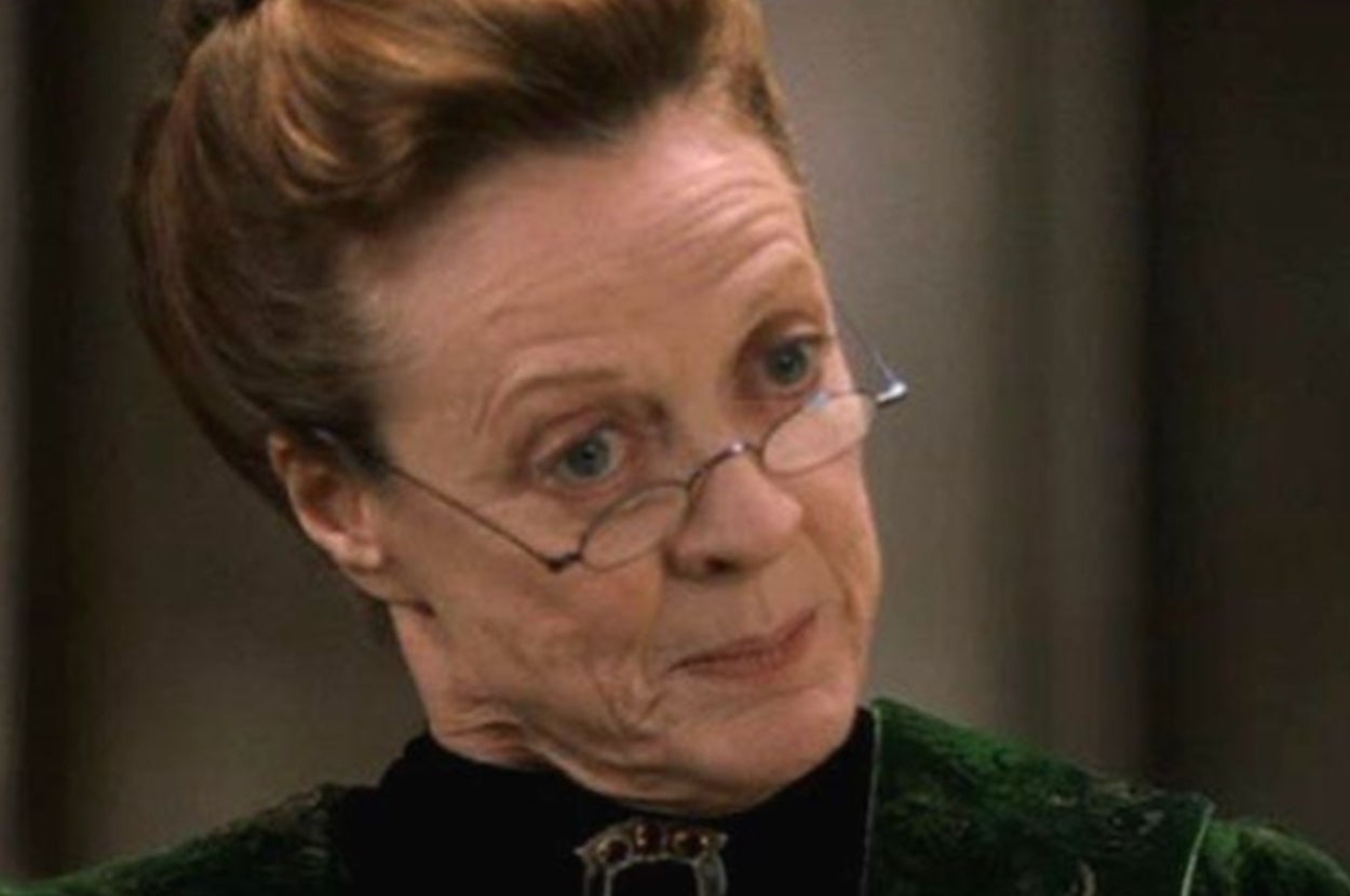 An older woman, wearing glasses, with hair styled up, appears to be in a serious conversation or listening intently