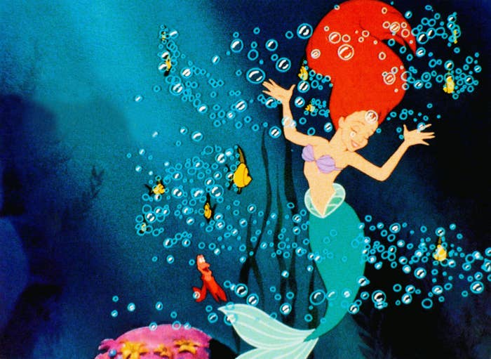 Animated mermaid with long hair swims joyfully surrounded by bubbles and sea creatures in an undersea scene