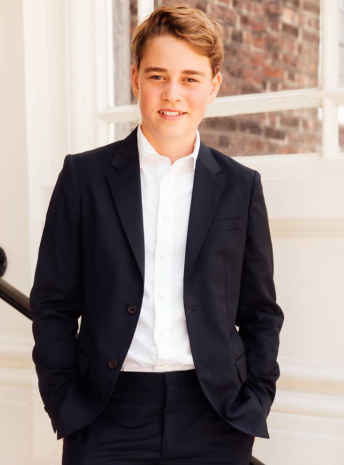 A young idiosyncratic   successful  a suit   and open-collared garment  stands confidently outdoors, hands successful  pockets, with a subtle smile