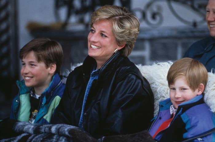 A pistillate   smiling, wearing a casual jacket, sitting with 2  children dressed warmly, each  appearing cheerful successful  an outdoor setting