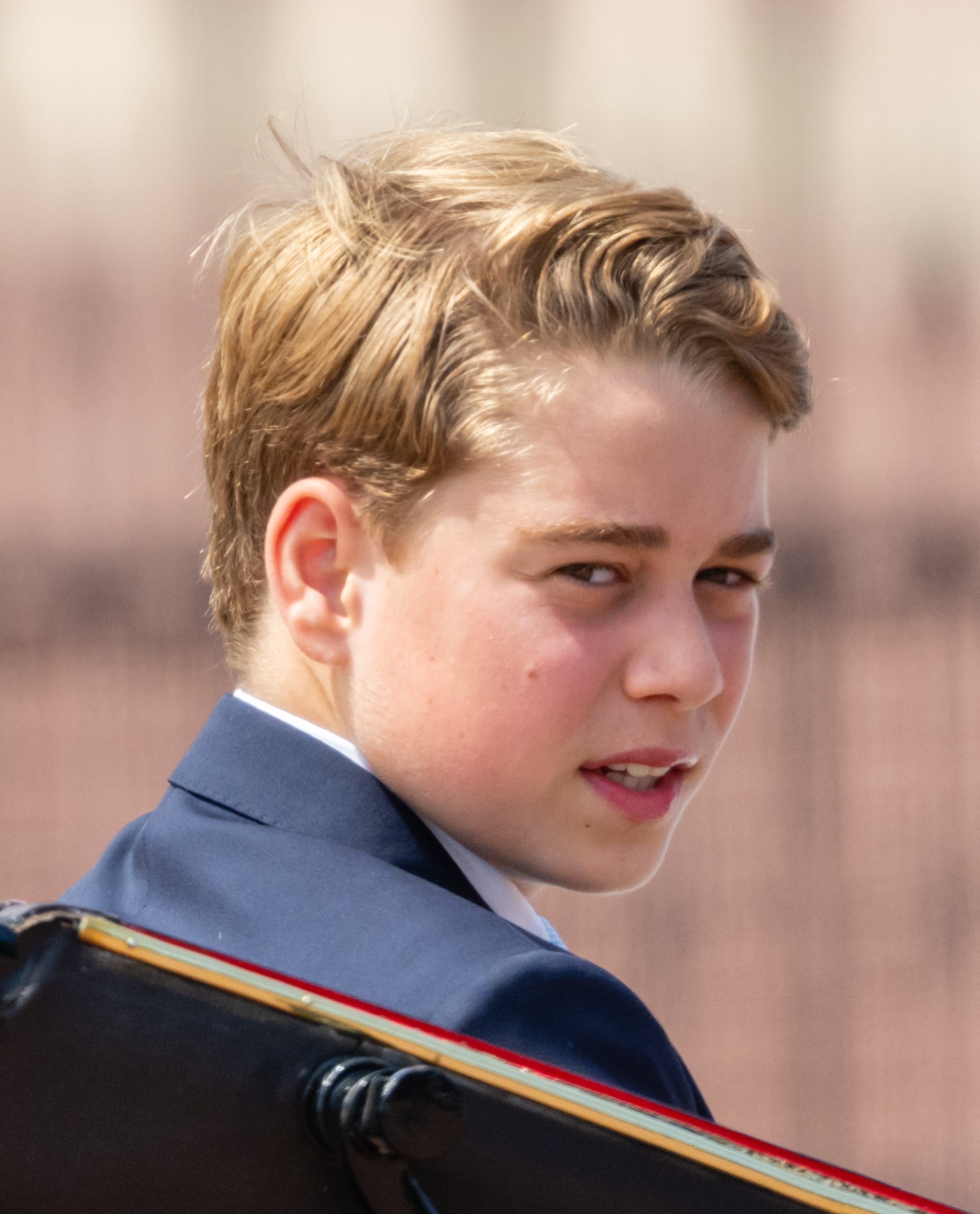 Young idiosyncratic   successful  a suit, glancing sideways with a neutral expression. Background is blurred, emphasizing the individual