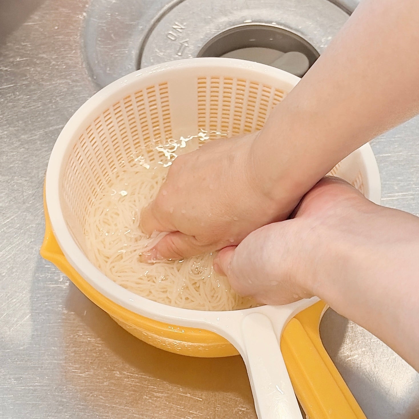 手でそうめんを水洗いしている様子。