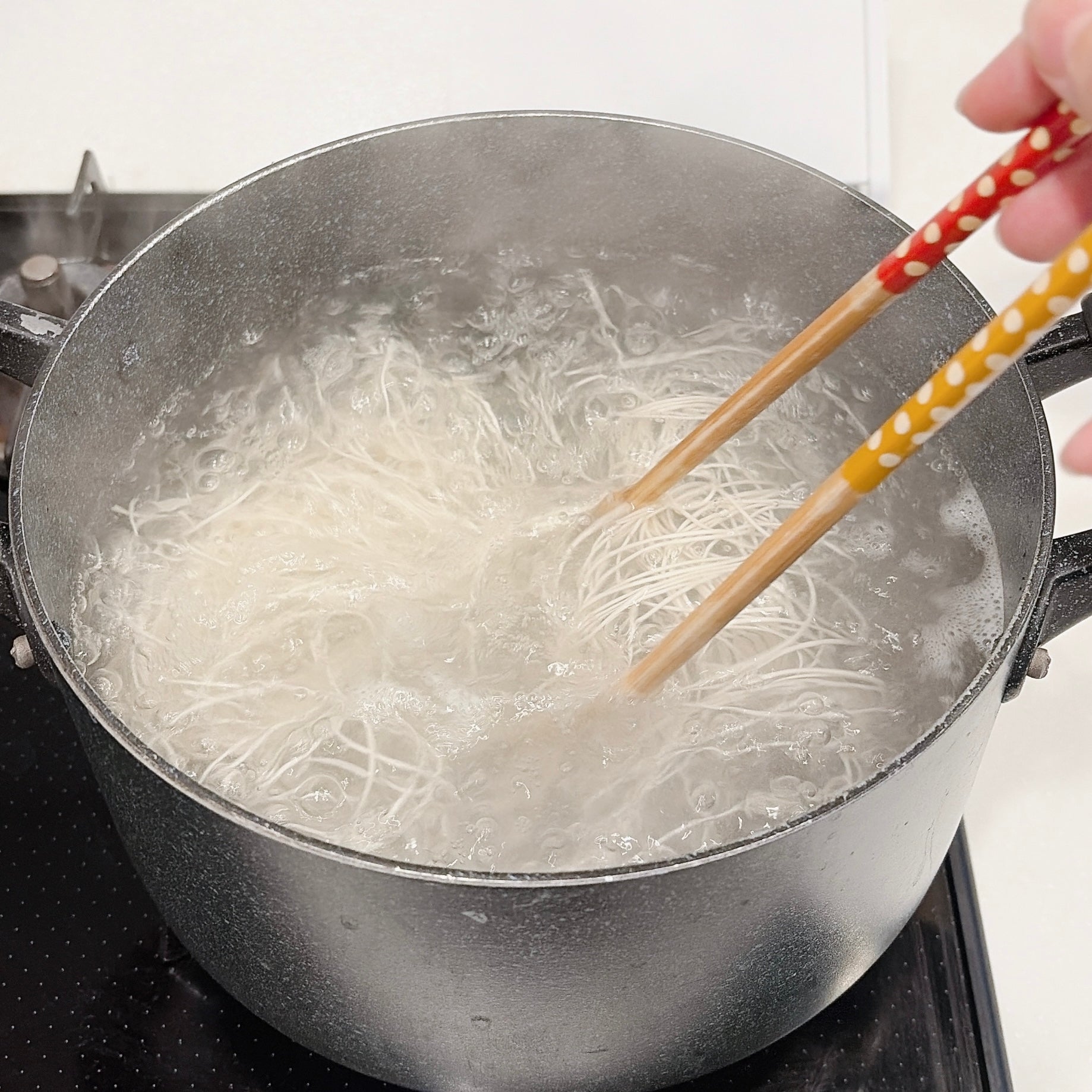鍋でそうめんをかき混ぜている様子。