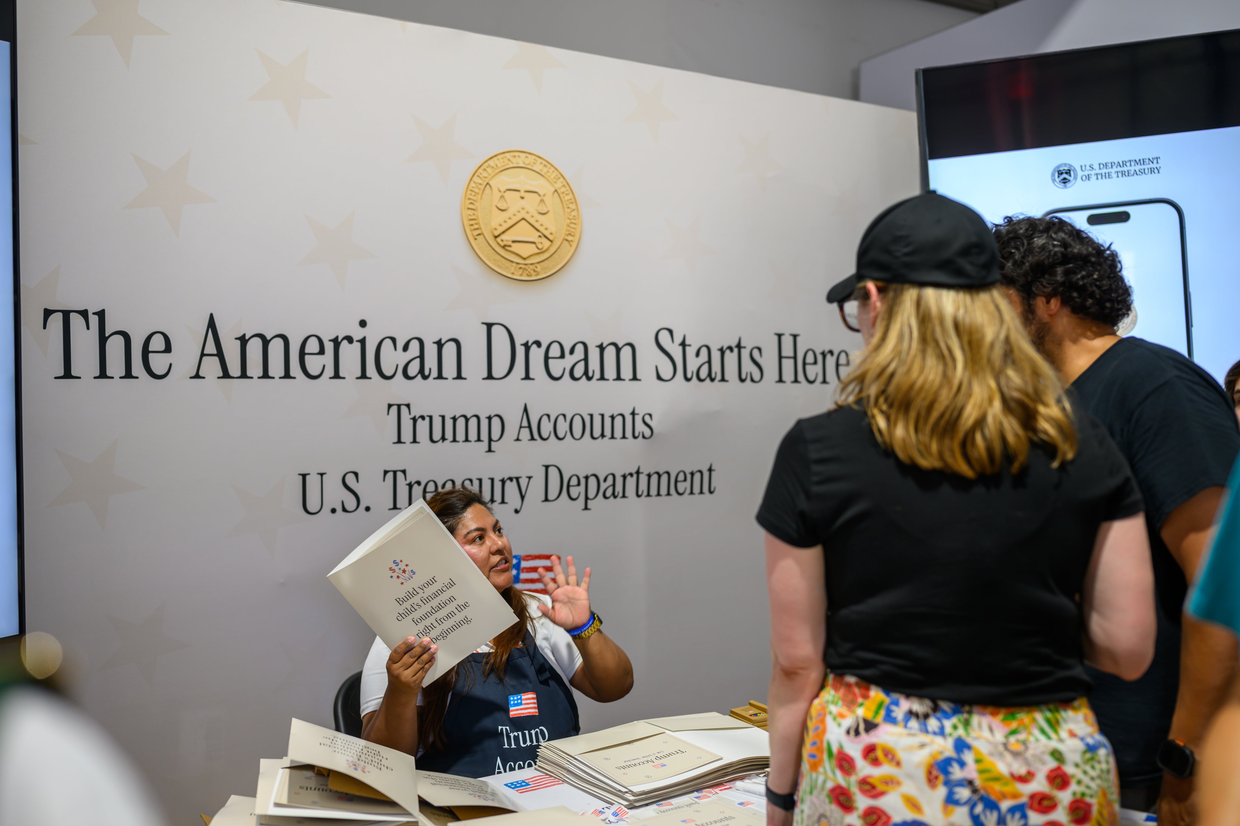 En person ved en amerikansk finansstand diskuterer informasjon om Trump-kontoer med en gruppe mennesker