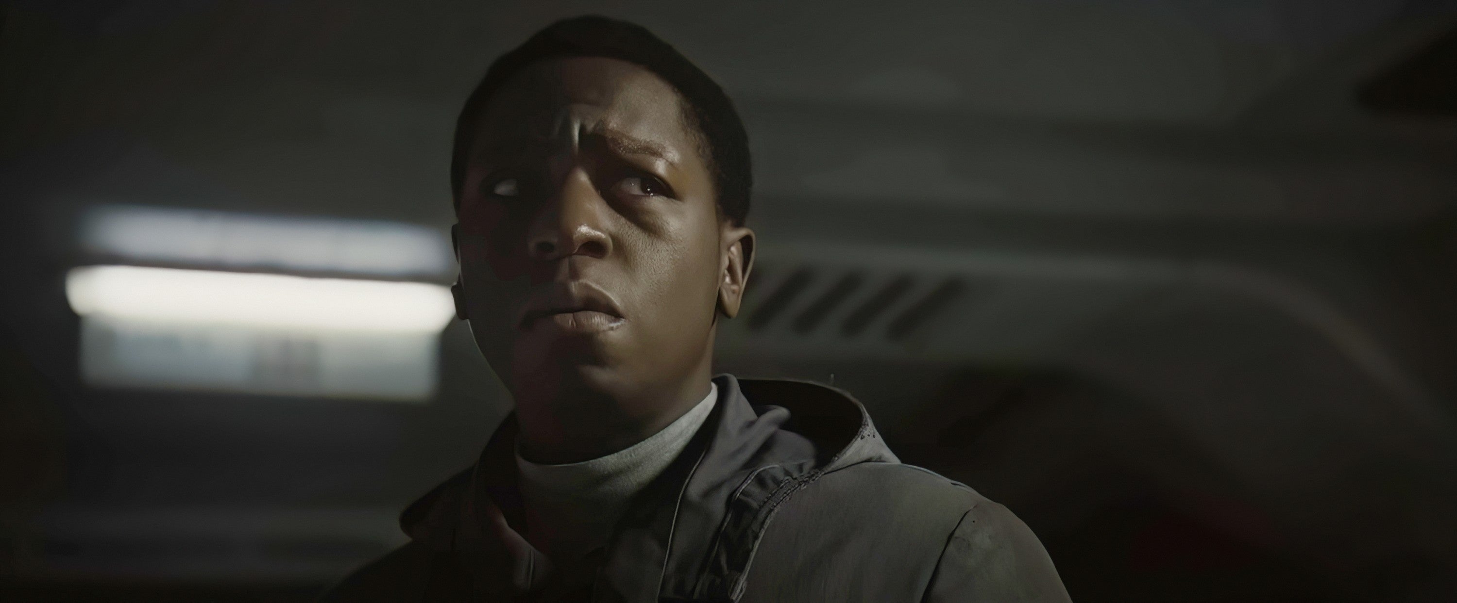 Person in a futuristic setting looking concerned or thoughtful, wearing a casual jacket. Appears to be a scene from a TV show or movie