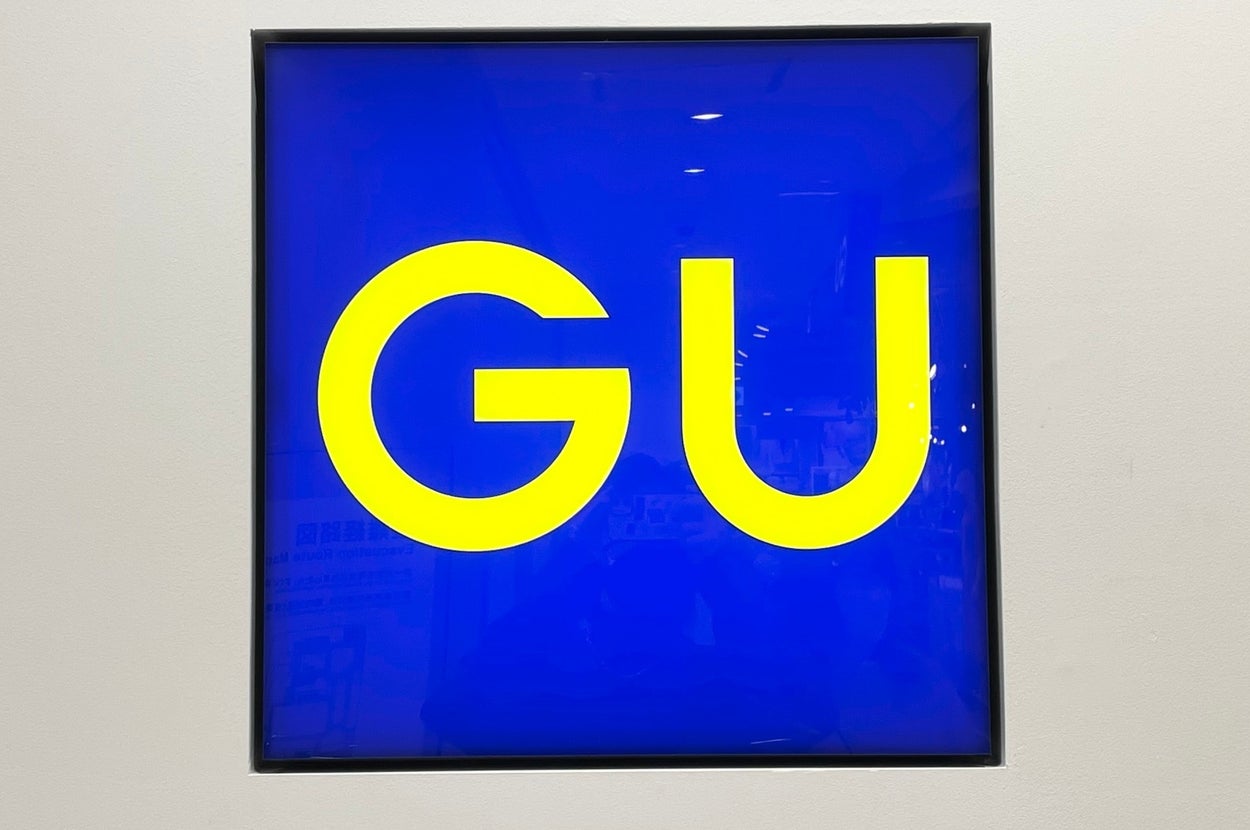 壁に掲示された「GU」ショップのロゴ。