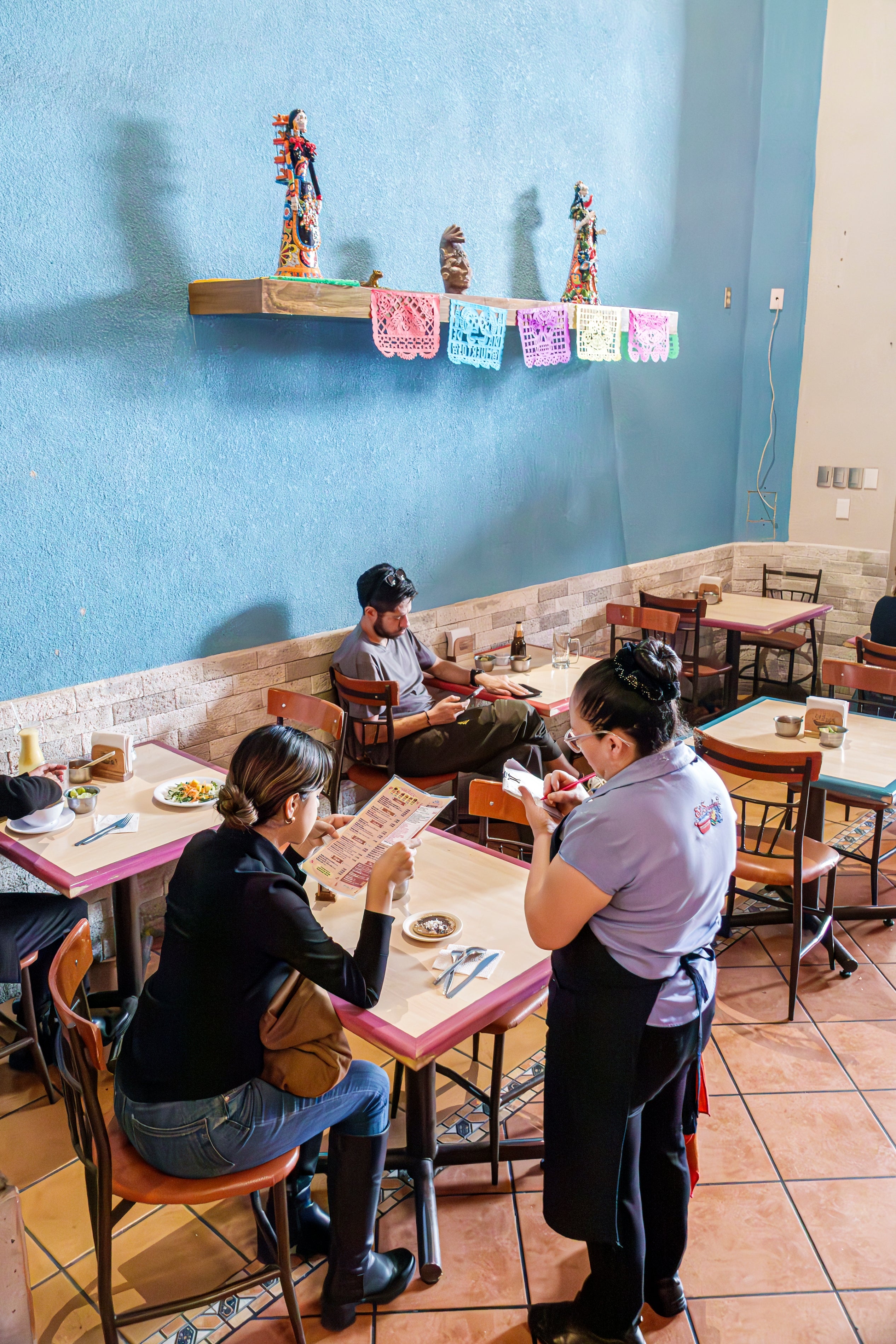 Folk som spiser på en liten restaurant med fargerike dekorasjoner og en server som tar en bestilling