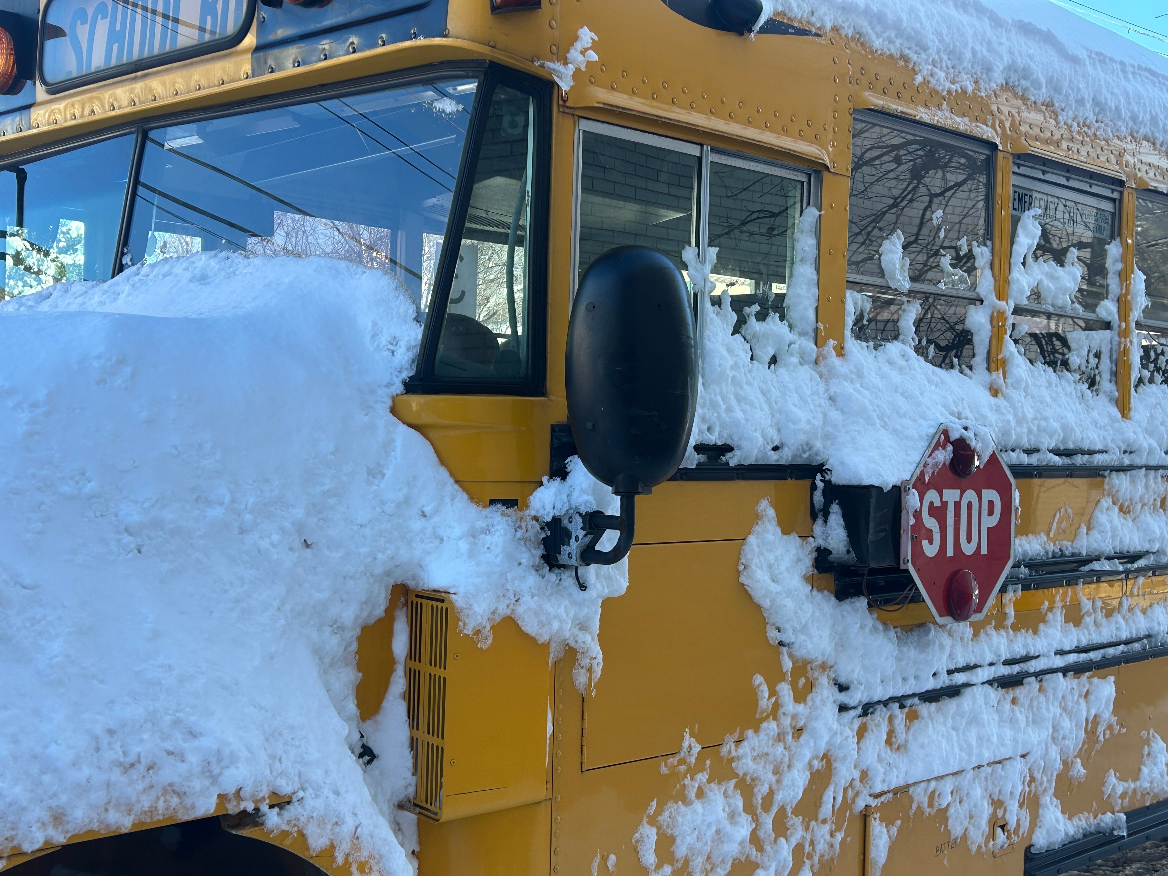 Skolebuss dekket av snø stoppet ved et stoppskilt