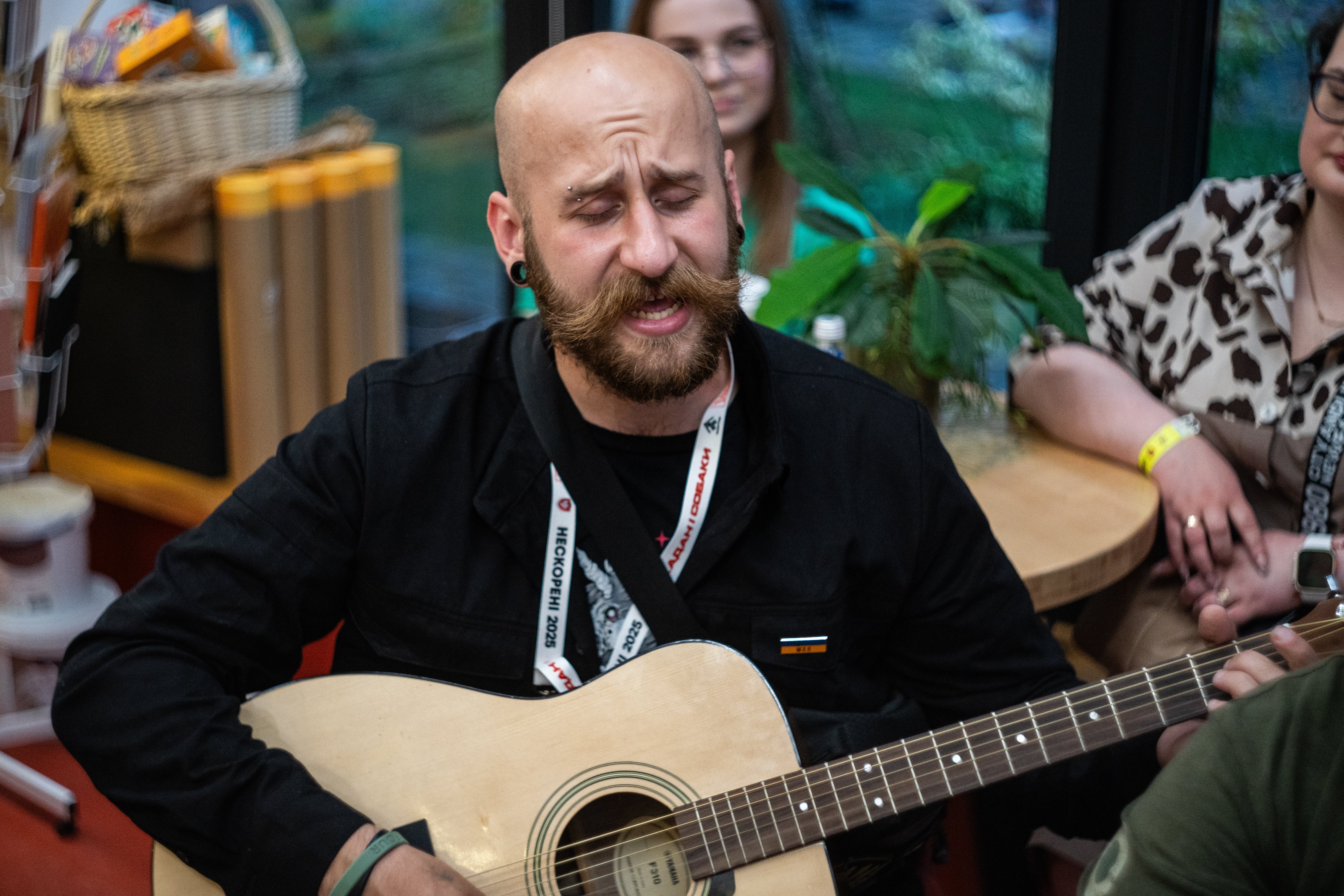 Mann med bart og skjegg spiller en akustisk gitar, lukkede øyne, i uformelle omgivelser