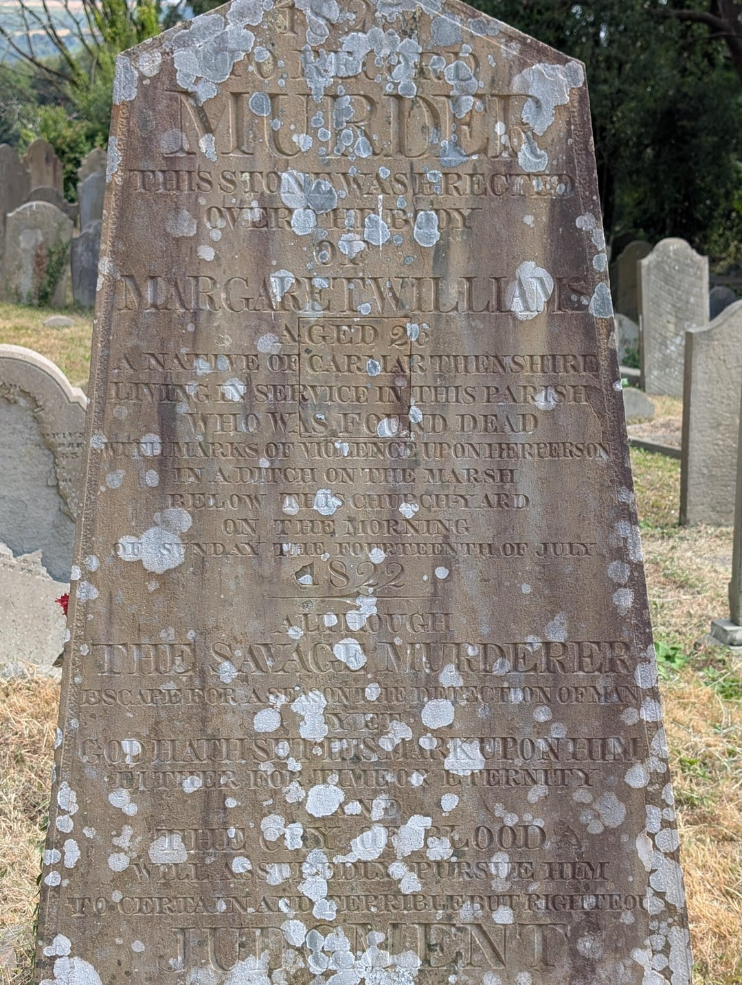 An aged gravestone with engraved text dedicated to Margaret Williams and Phil Savage, mentioning their lives and deaths in the 1800s