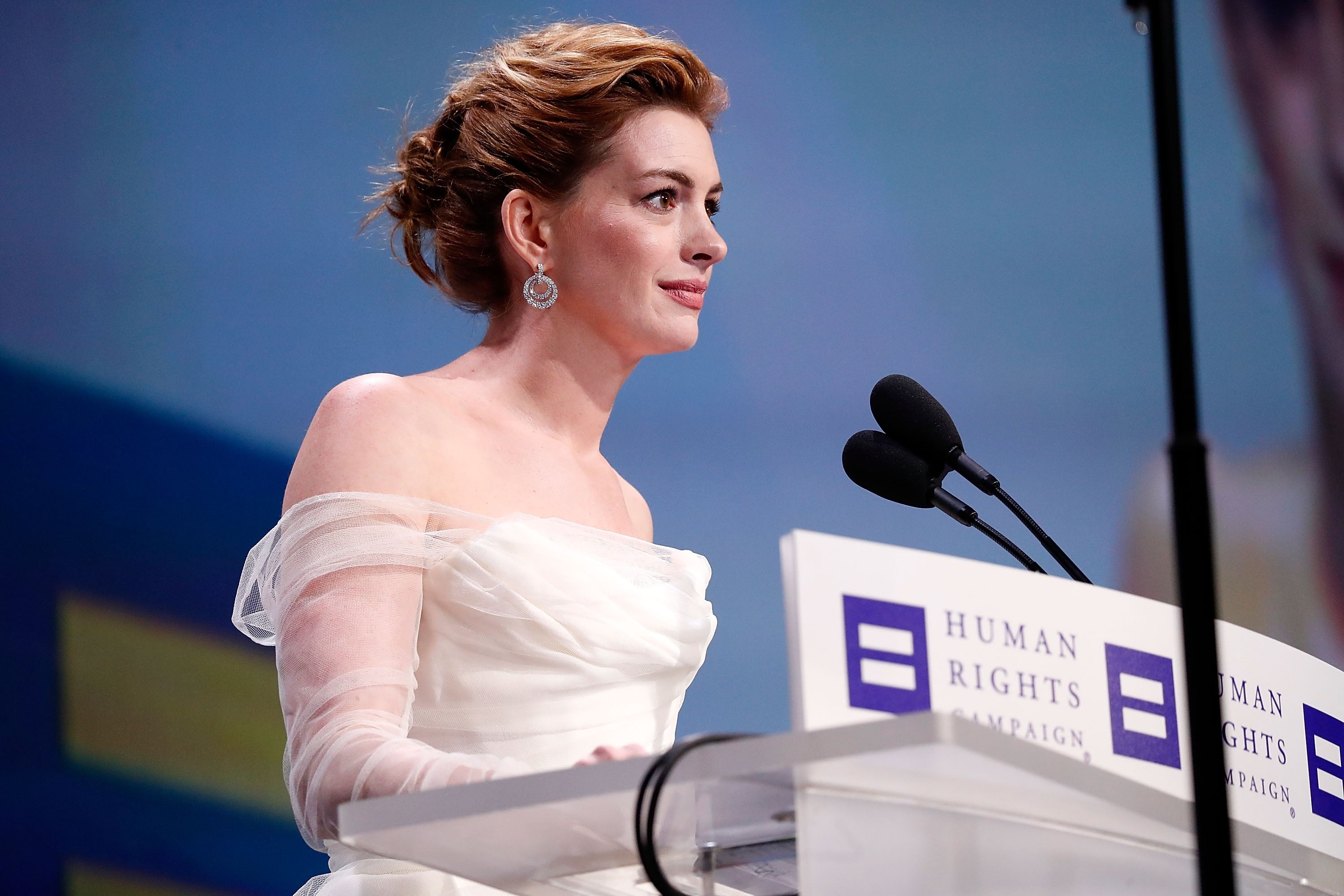 Person in an elegant off-shoulder gown speaks at a podium with Human Rights Campaign logos