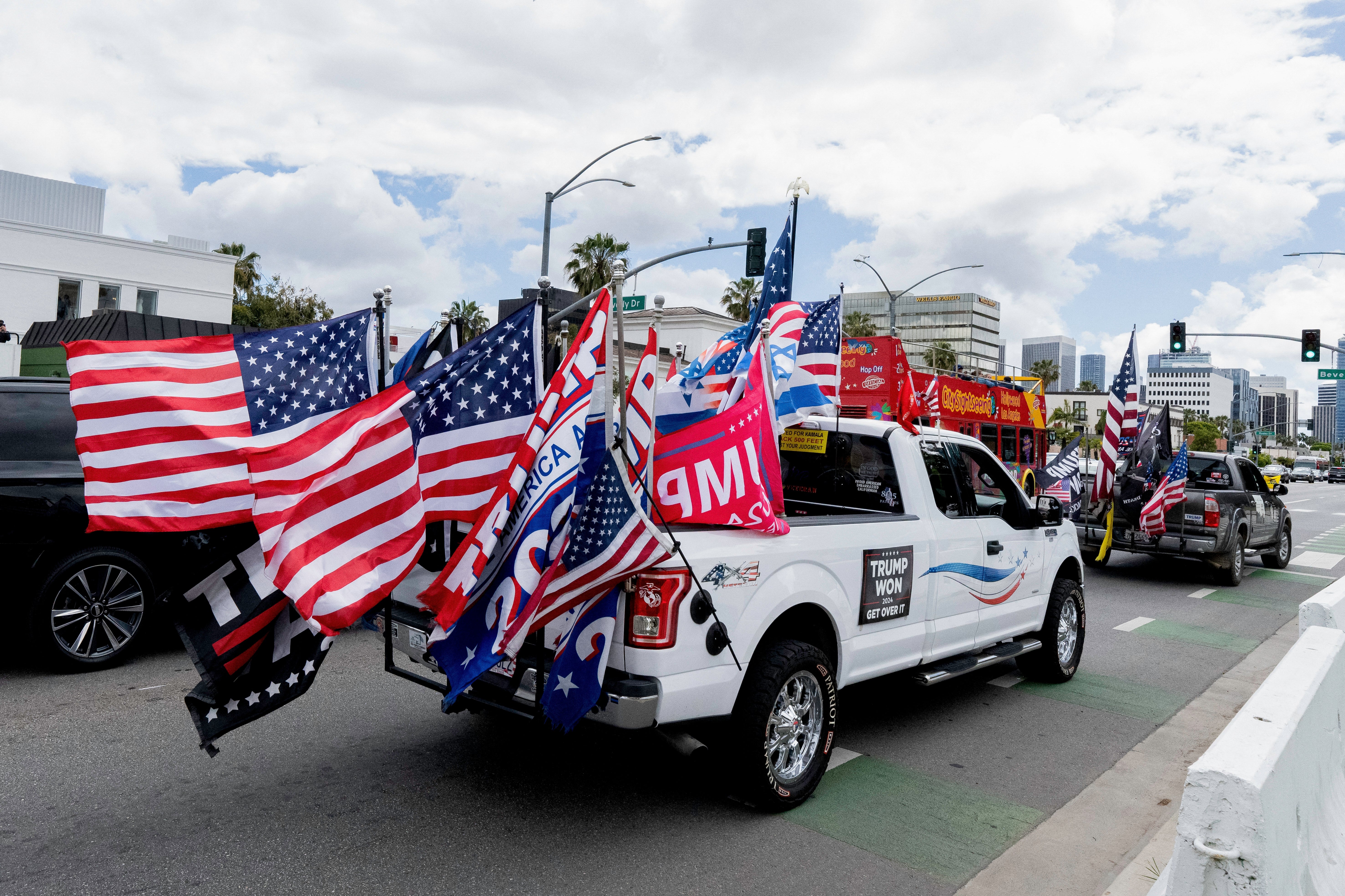 En lastebil dekorert med flere flagg, inkludert amerikanske flagg og politiske flagg, deltar i et gatemøte