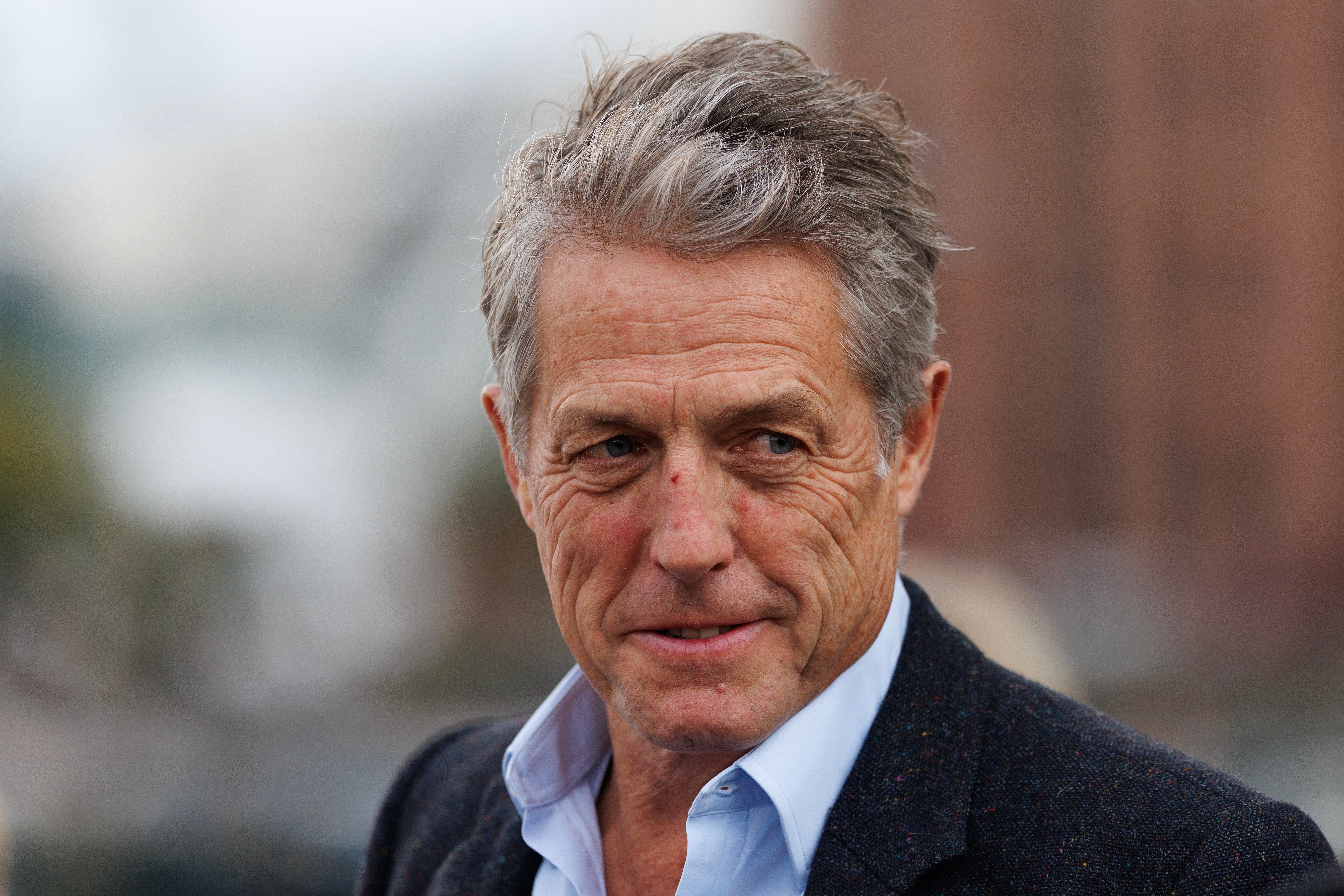Man in a suit with a light shirt, looking to the side, outdoors