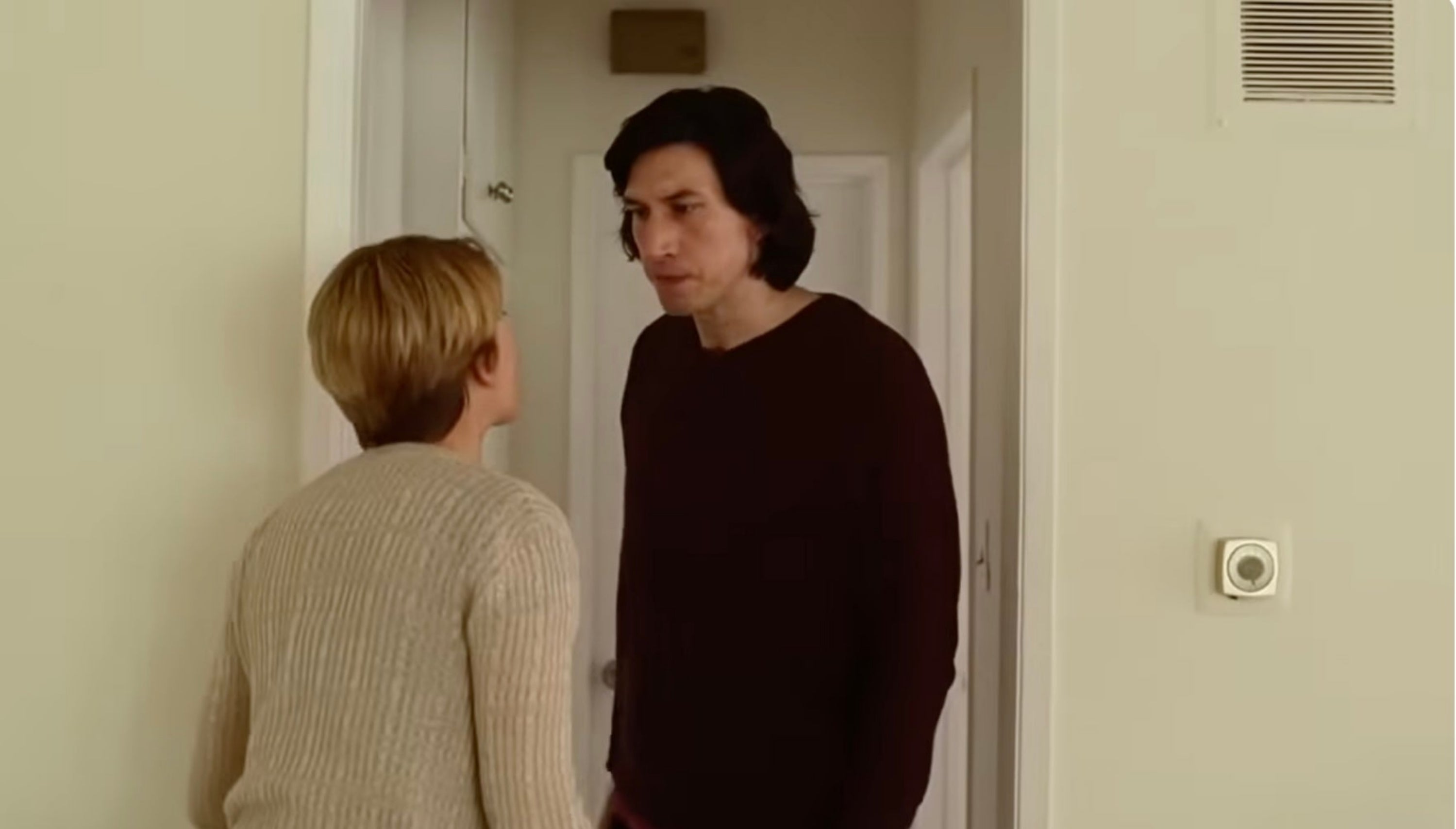 Two people face each other in a hallway, engaging in a tense conversation