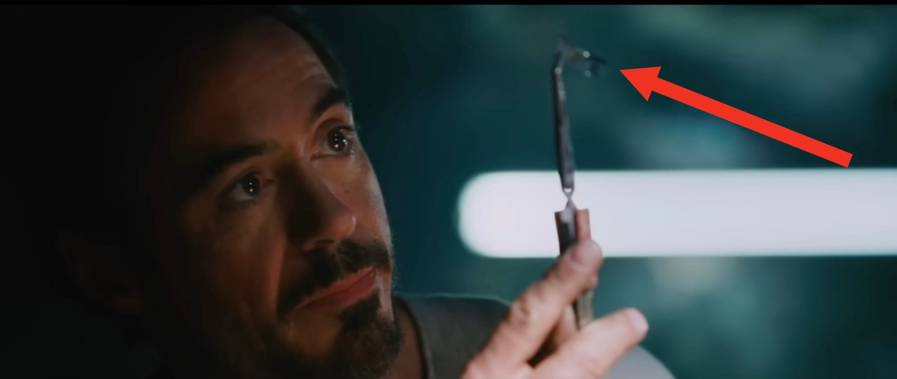Person examining a small device with intense focus in a dimly lit setting