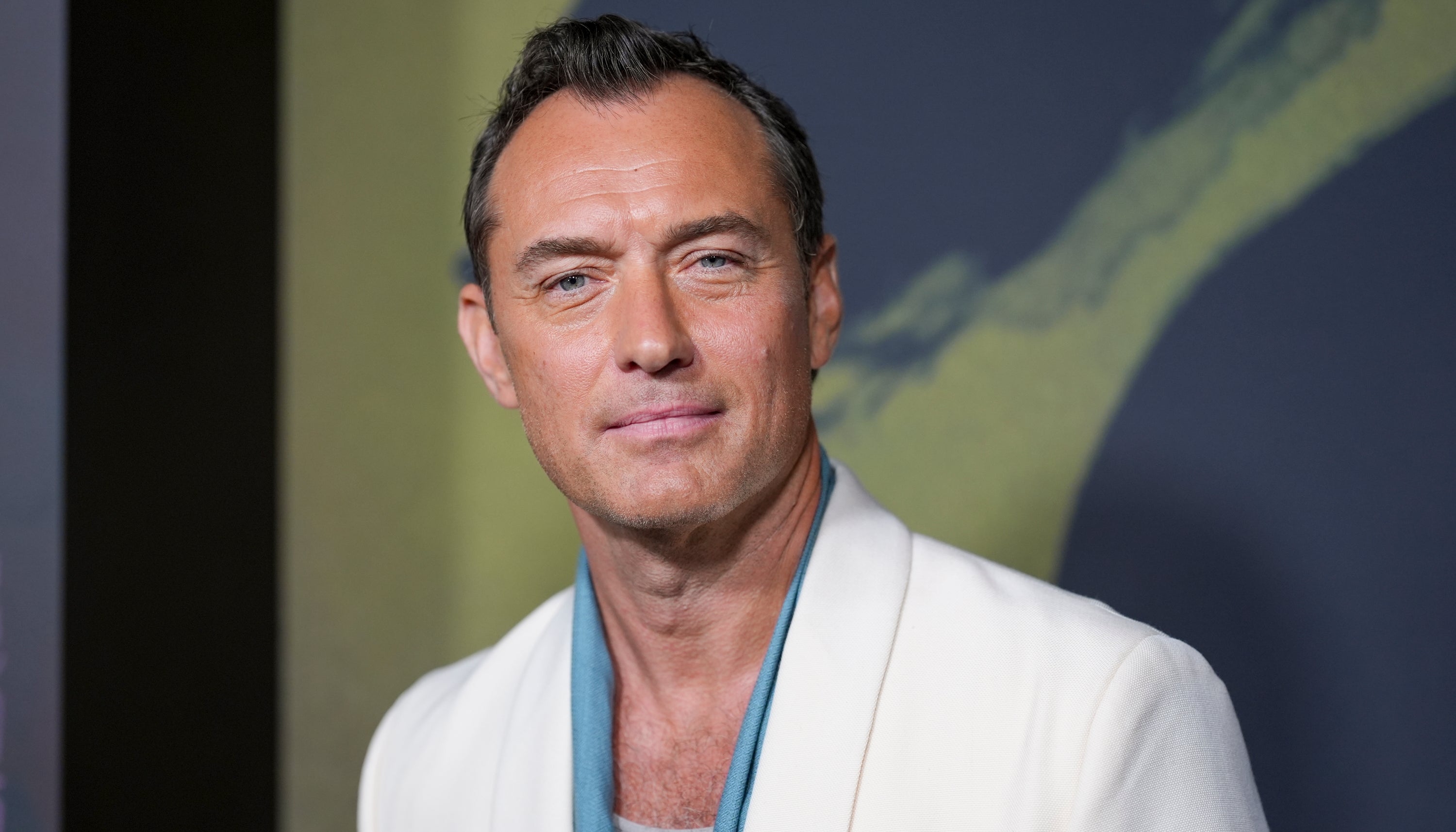 A person in a stylish white blazer with a teal scarf, attending an event