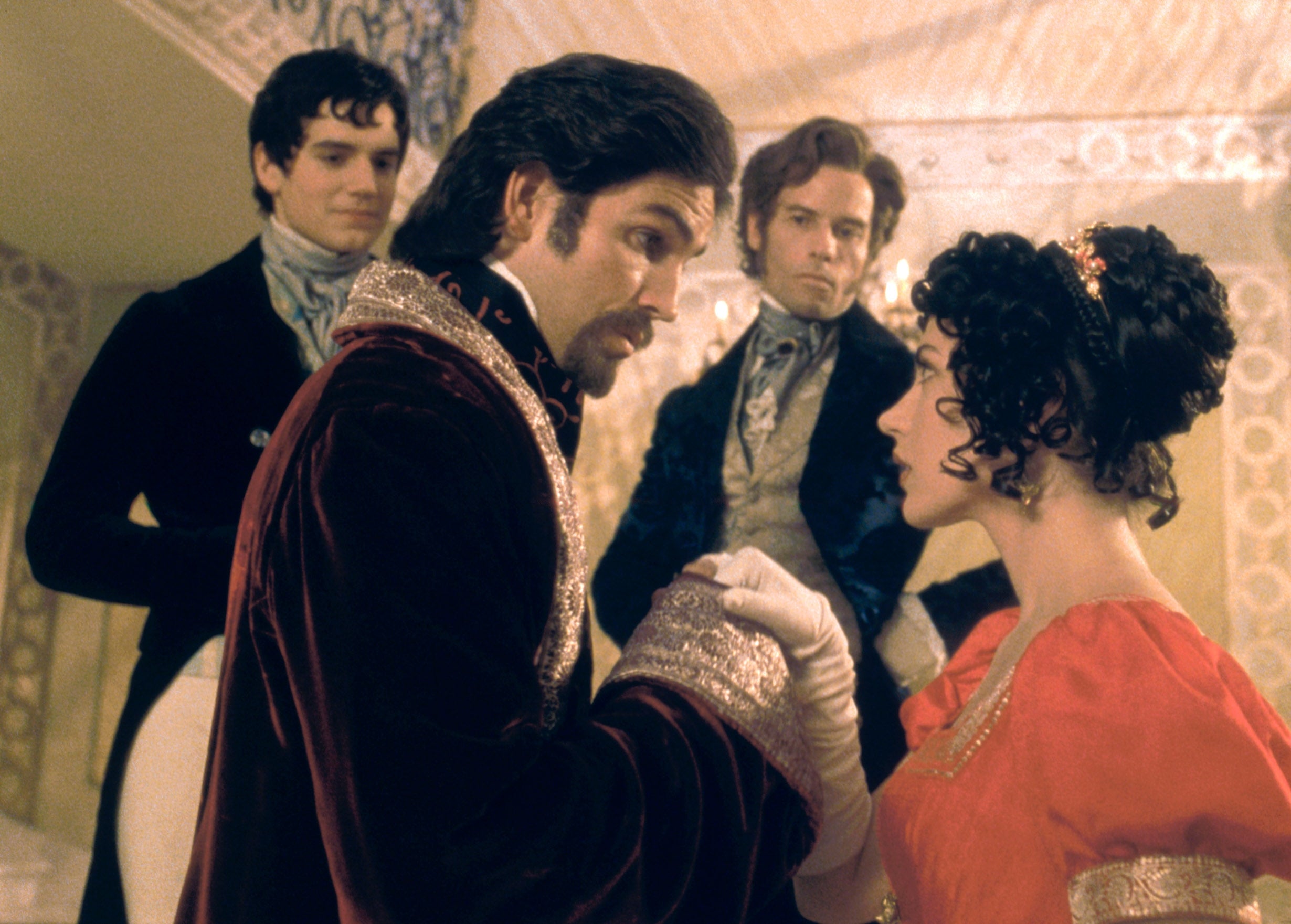 Victorian-era dressed individuals in conversation; man in velvet coat, woman in elegant gown with gloves. Two men in the background observe