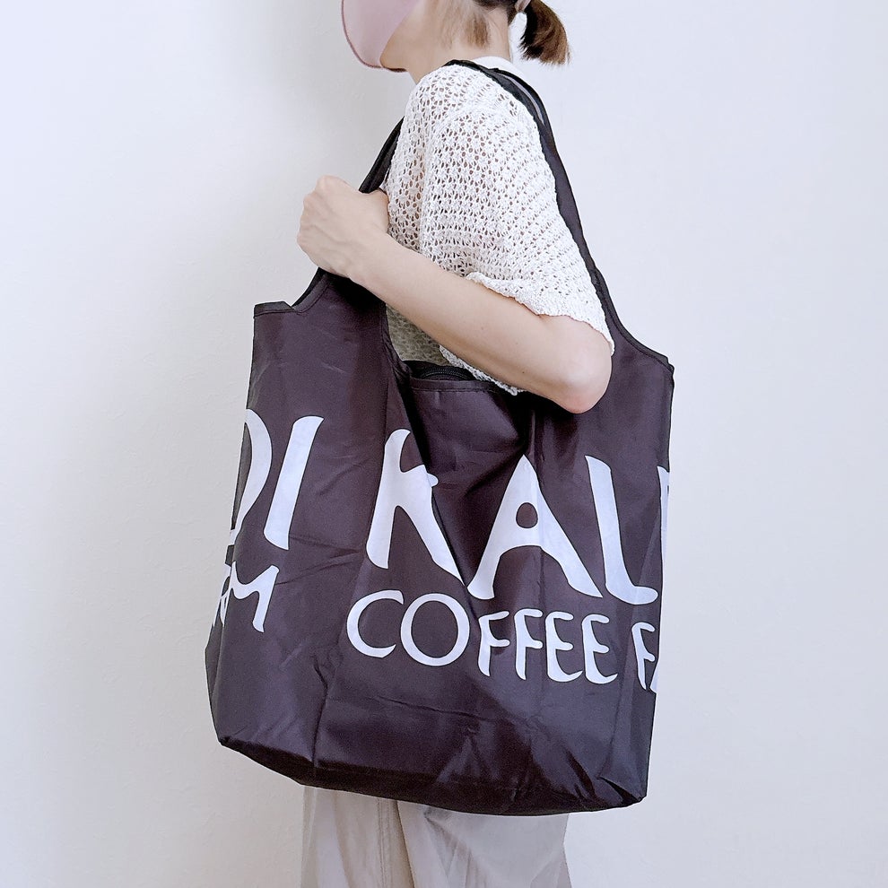 KALDI（カルディ）の「コンパクト保冷バッグ ブラック 1枚」肩にかけて持っている様子。