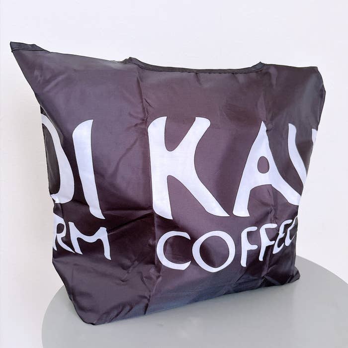 KALDI（カルディ）の「コンパクト保冷バッグ ブラック 1枚」荷物が入った状態で、テーブルの上に置かれている様子。