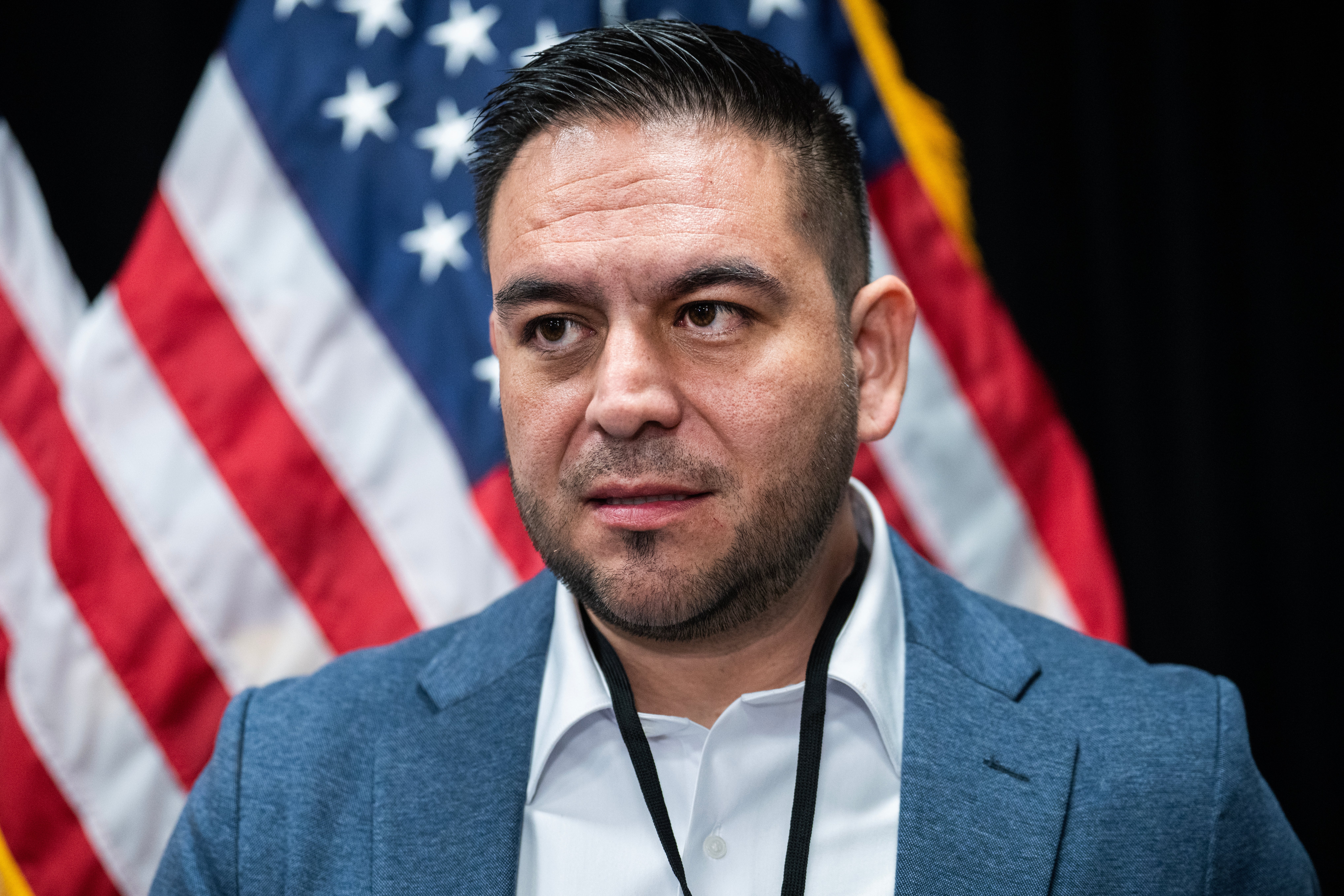 En person i dress står foran amerikanske flagg og dukker opp på en formell begivenhet
