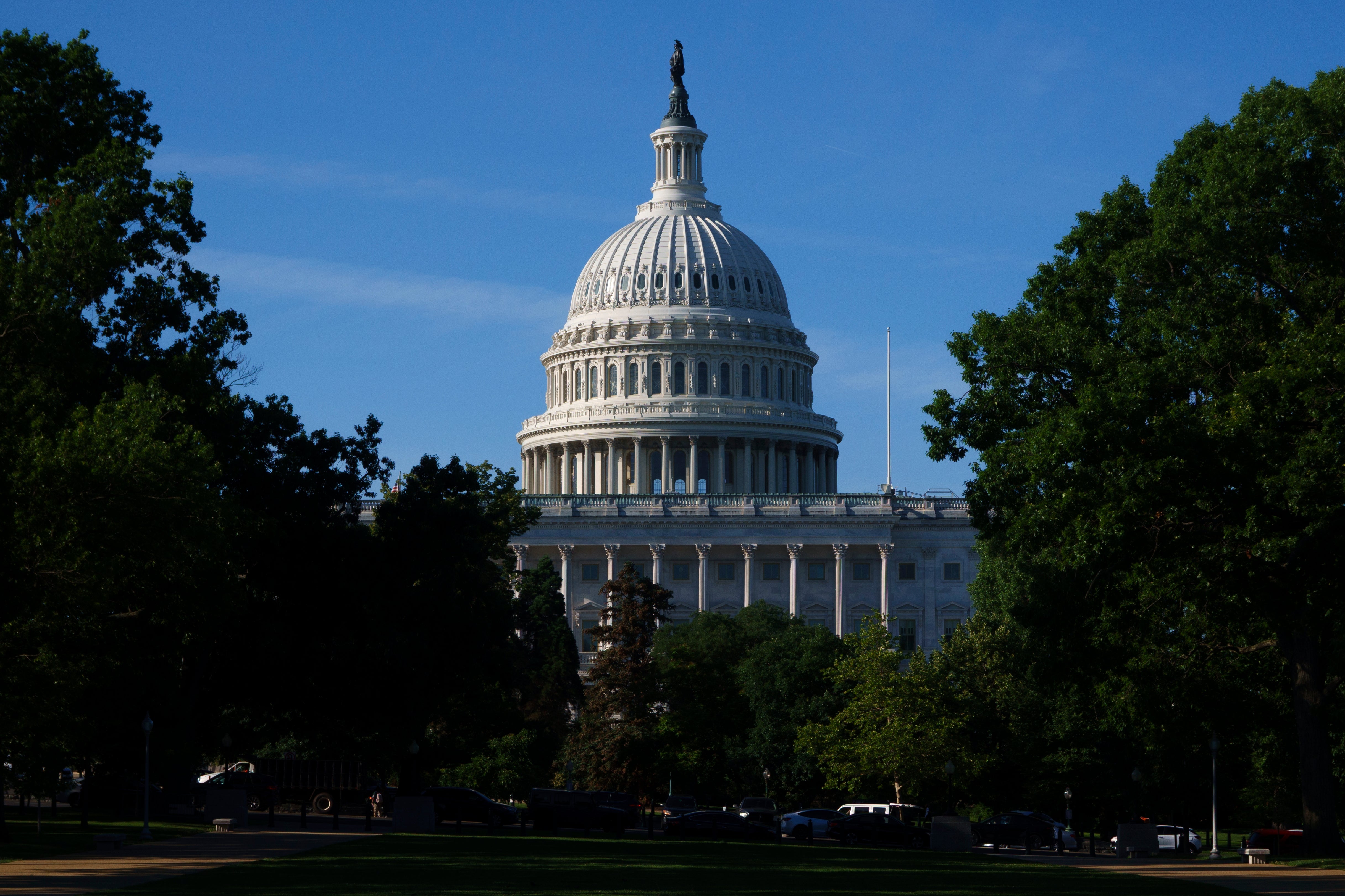 US Capitol-bygning med klar himmel, omgitt av trær, som indikerer en fredelig dag i Washington DC