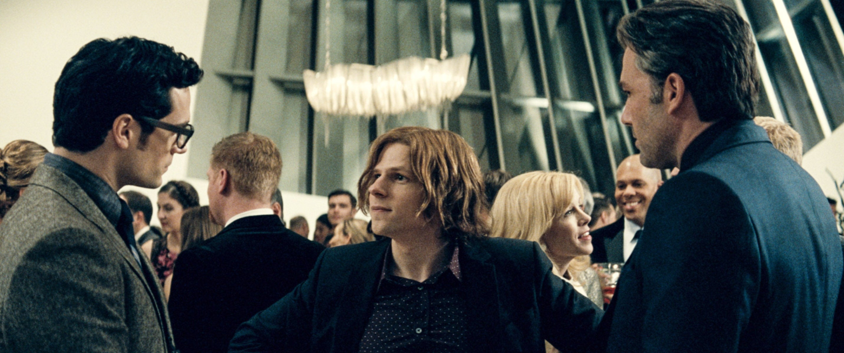 Henry Cavill, Jesse Eisenberg, and Ben Affleck at a formal event, engaged in conversation