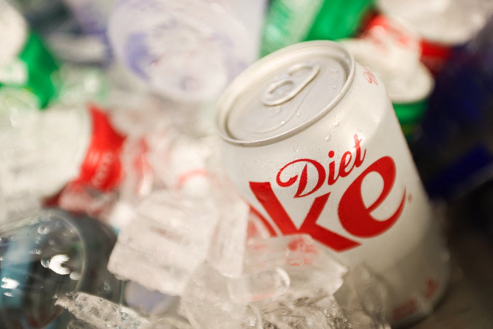 A can of Diet Coke rests in a pile of ice among other drink cans