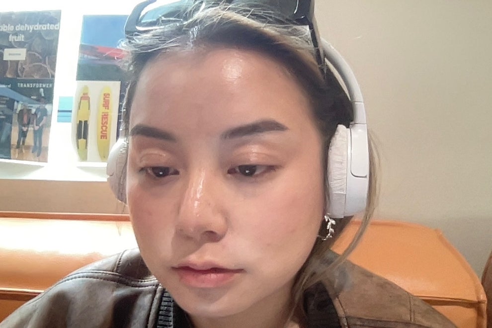 Person wearing headphones and sunglasses indoors, seated on an orange couch, appears focused or in thought