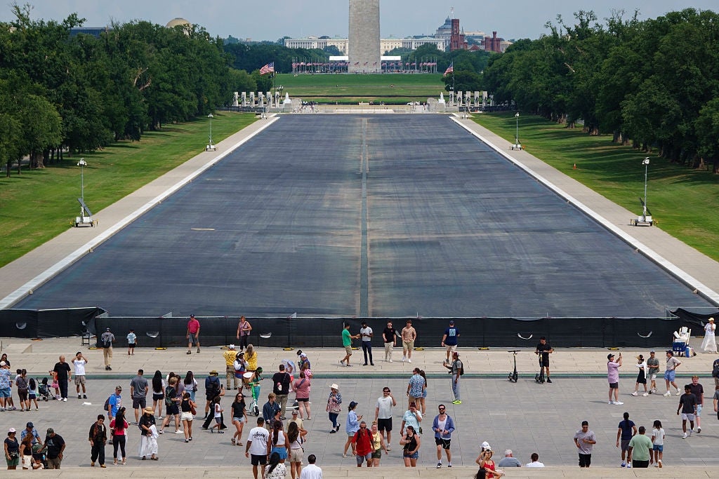 Folk som besøker Lincoln Memorial Reflecting Pool, drenert for vedlikehold, med Washington-monumentet synlig i bakgrunnen