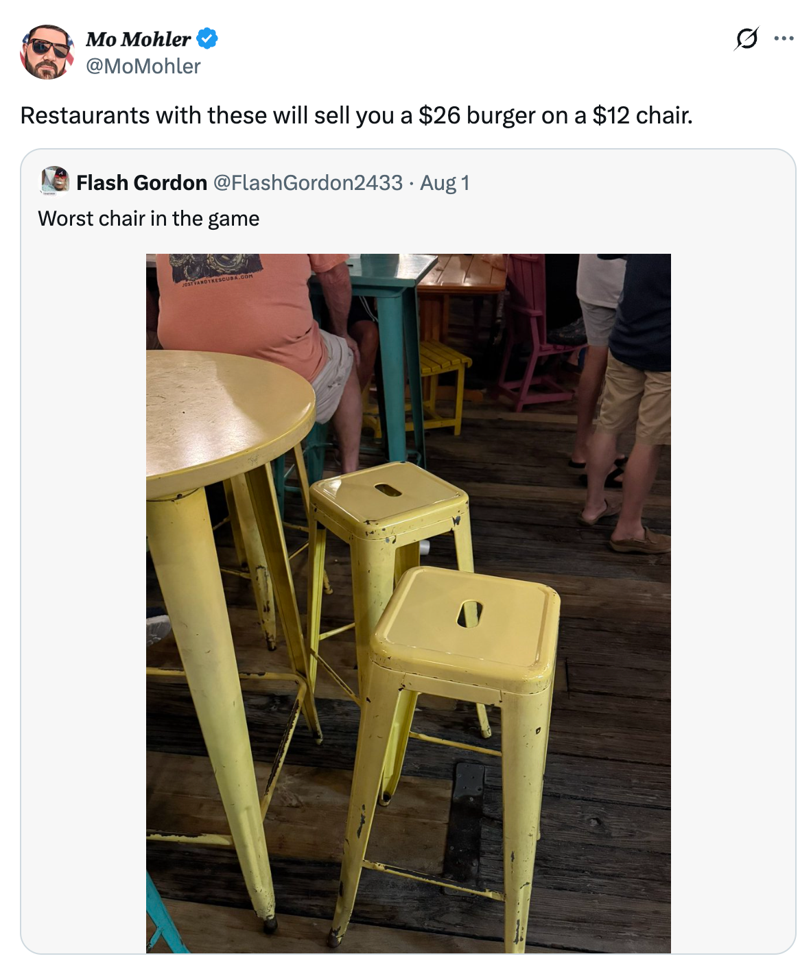 To gule metallkrakker og et matchende bord i en restaurant. En tweet vitser om dyre burgere og ukomfortable sitteplasser