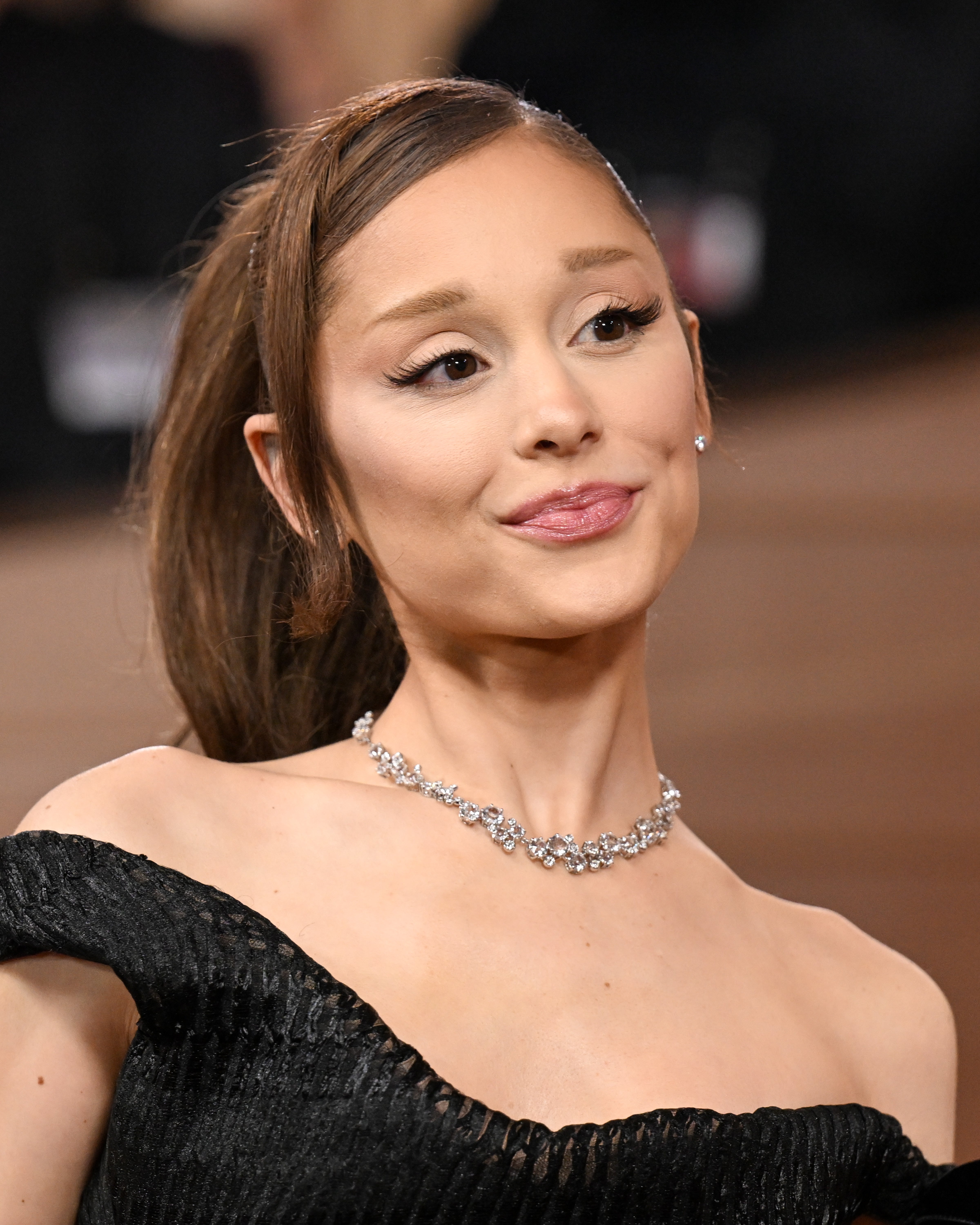 Person in elegant off-the-shoulder gown with a diamond necklace, posing at an event