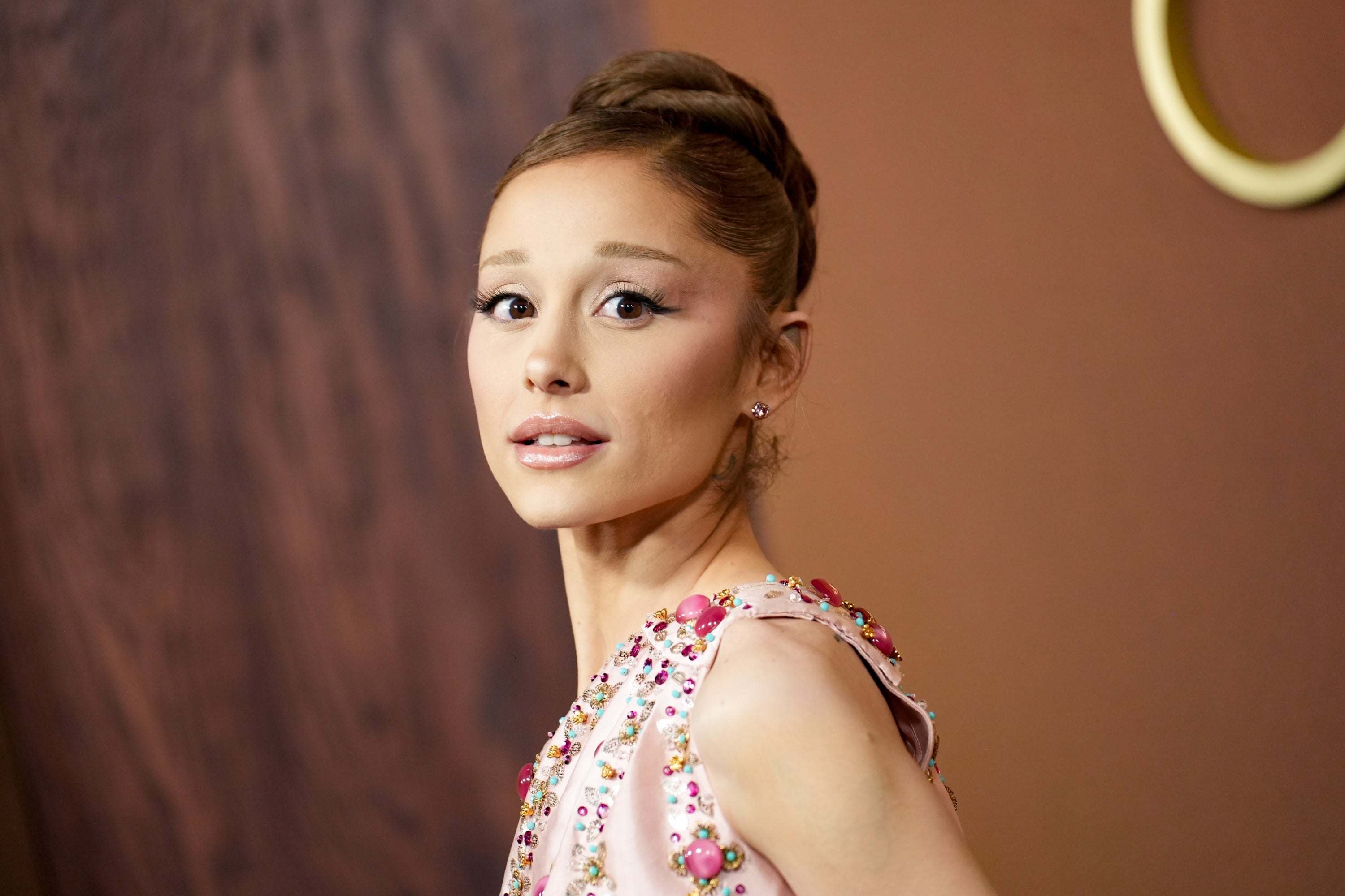 Person in embellished dress with sleek updo looks over shoulder at an event