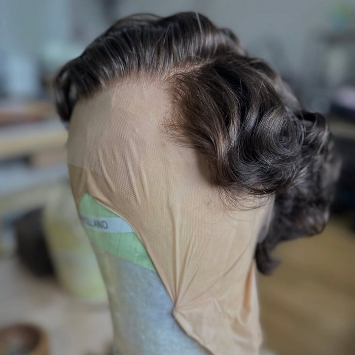 Realistic brown wig styled in loose waves on a mannequin head inside a room