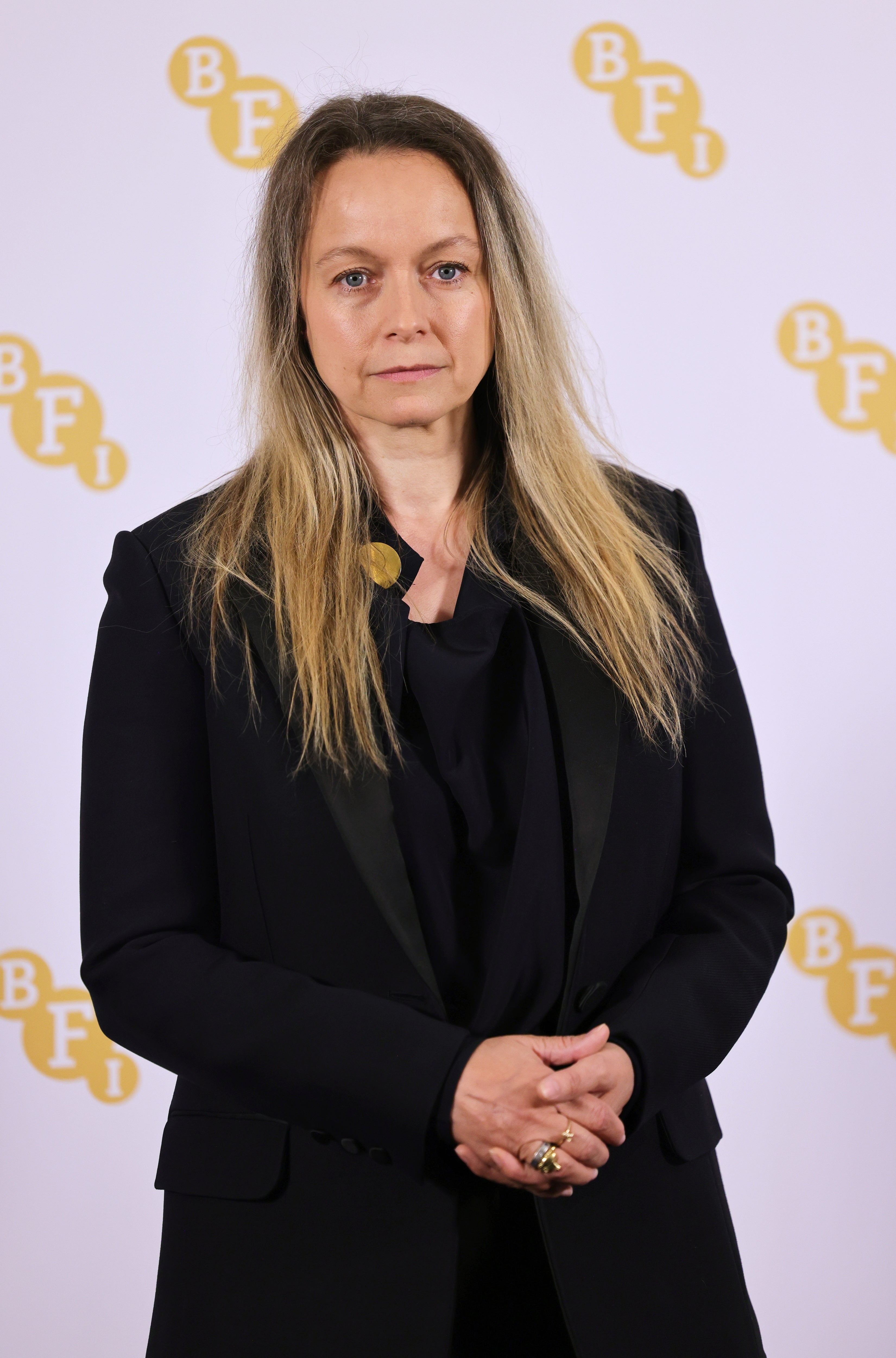 Person in a black suit and shirt at a BFI event, standing with a neutral expression