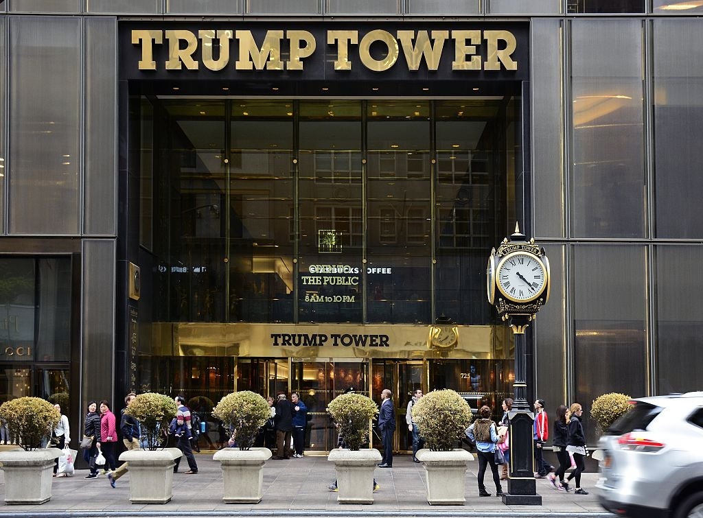 Folk som går foran inngangen til Trump Tower, med en stor klokke og gyldne bokstaver synlige