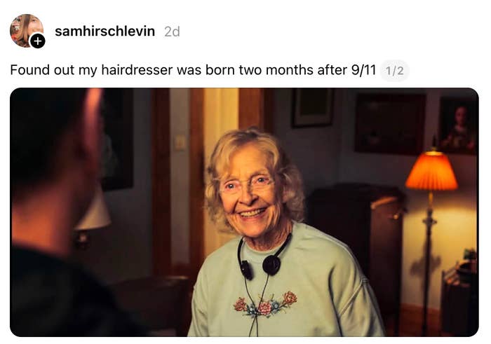 An elderly woman with headphones around her neck smiles warmly in a cozy room