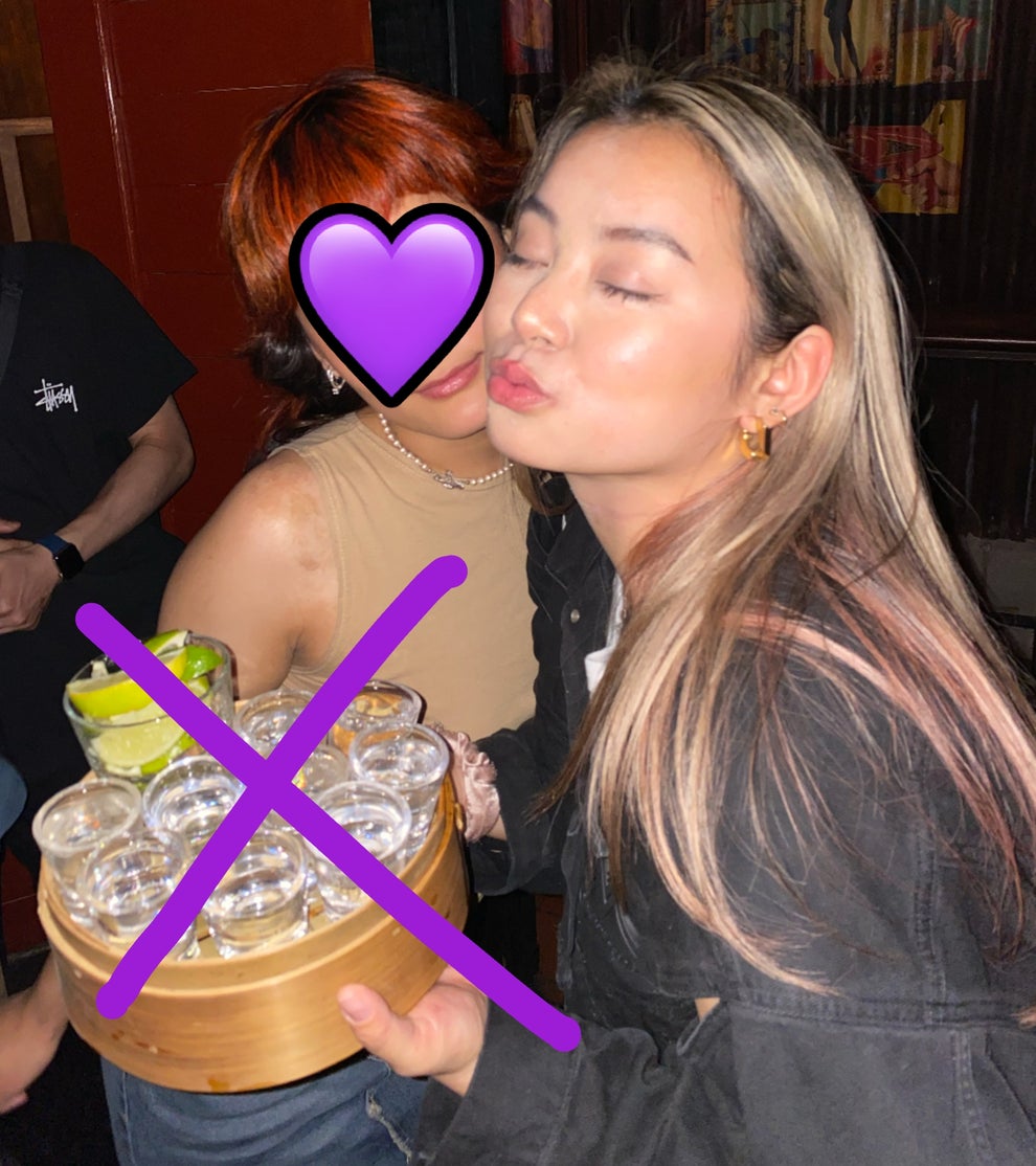 Two people with drinks at a lively bar, one holding a tray of shots with lime wedges. A festive and social atmosphere