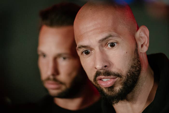 Two men with facial hair look intently in the same direction, one in the foreground and one slightly blurred in the background