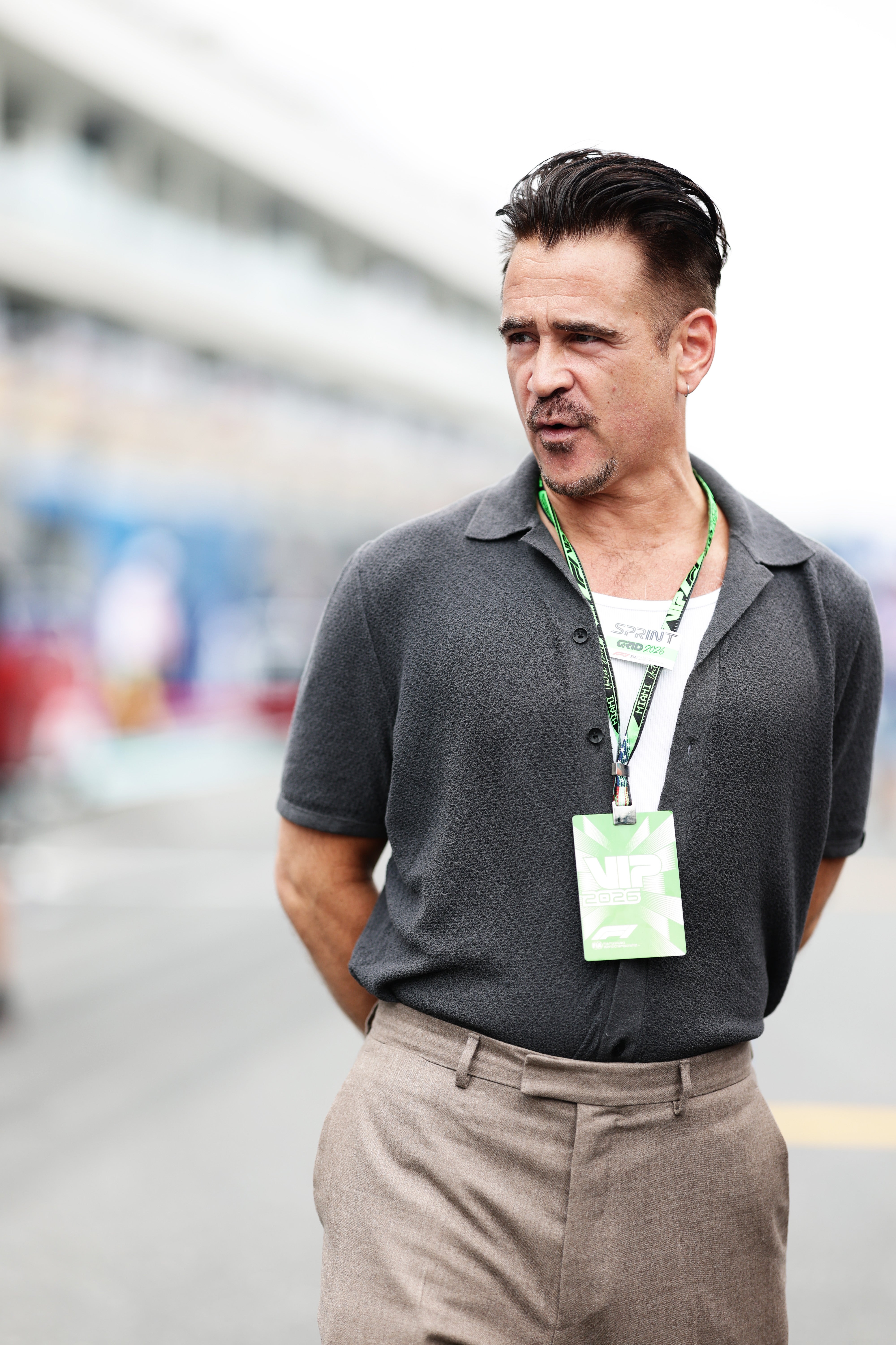Person in a casual outfit with a lanyard around their neck, standing outdoors on a busy street or event location