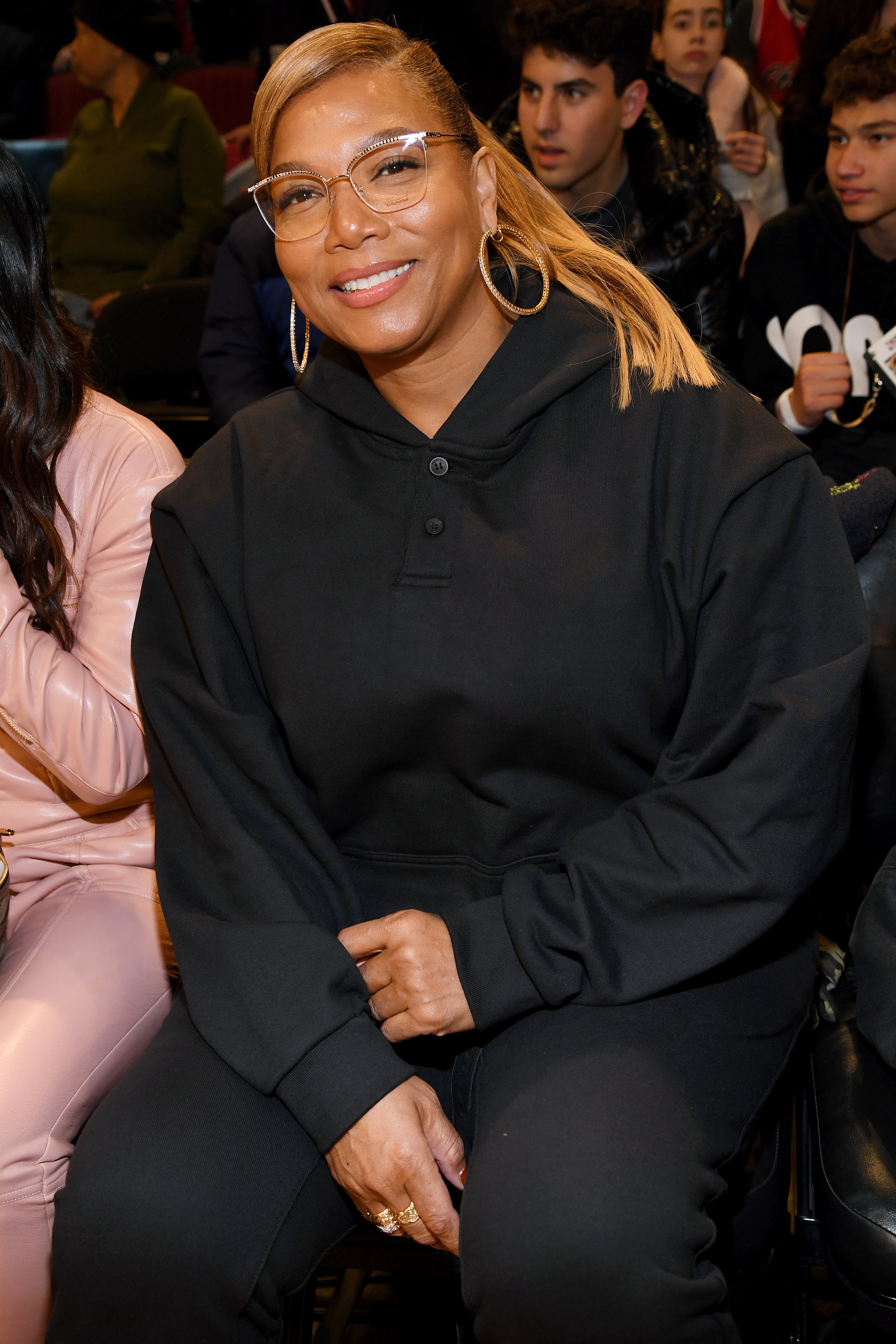 Person in a stylish, casual black hoodie, seated and smiling at an event
