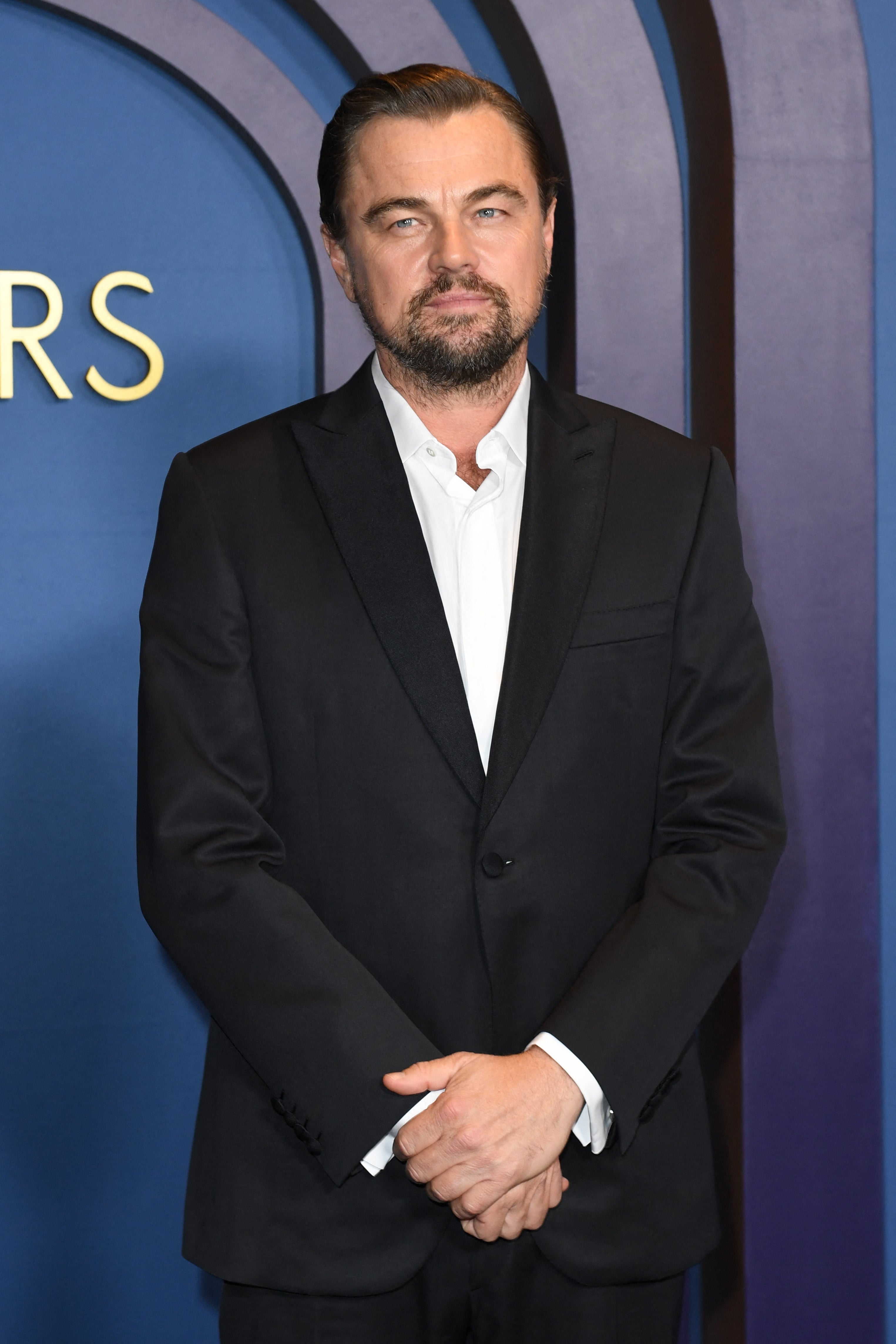Person in a tailored suit standing at an event, posing with a composed expression