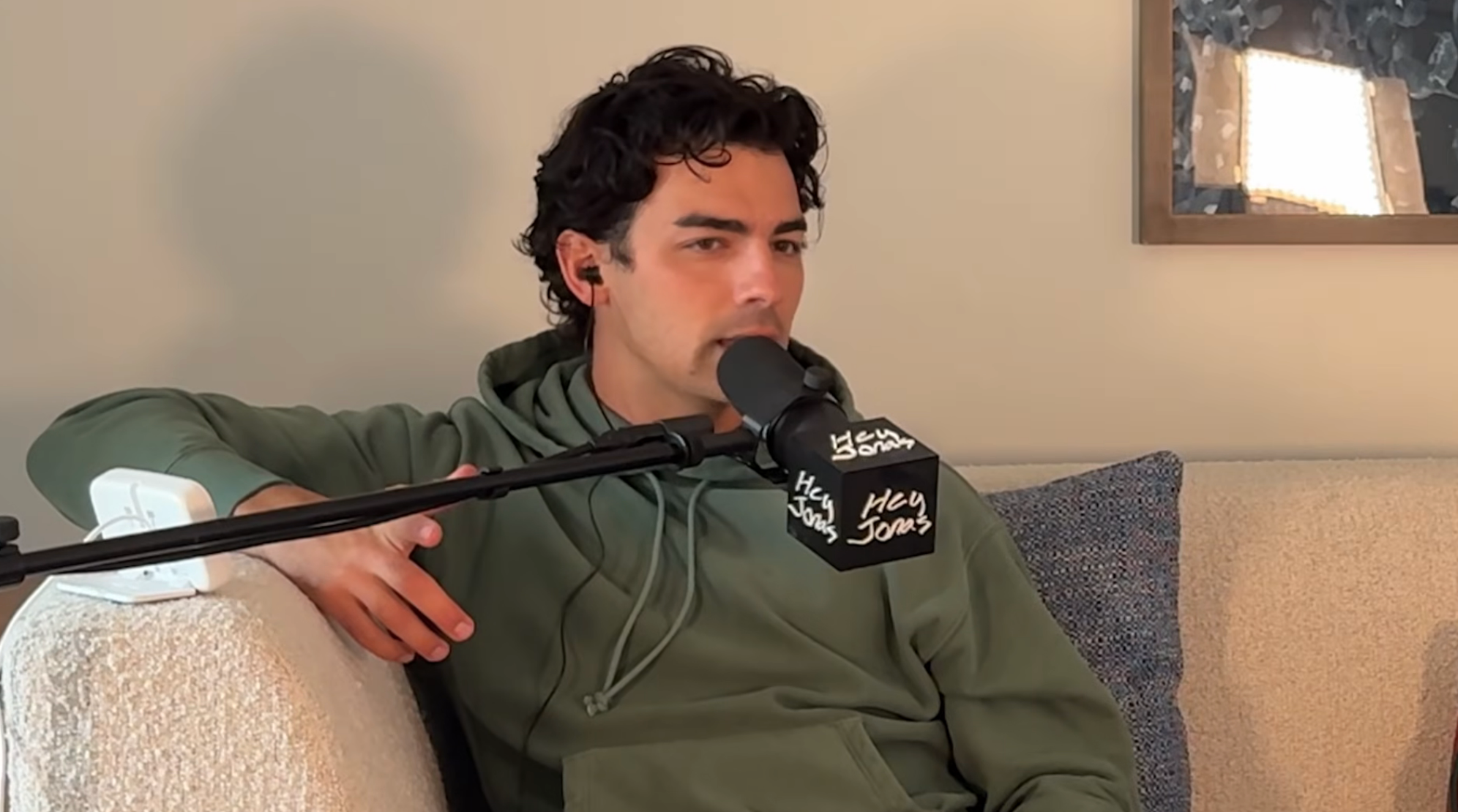 Person in a hoodie speaking into a microphone on a podcast