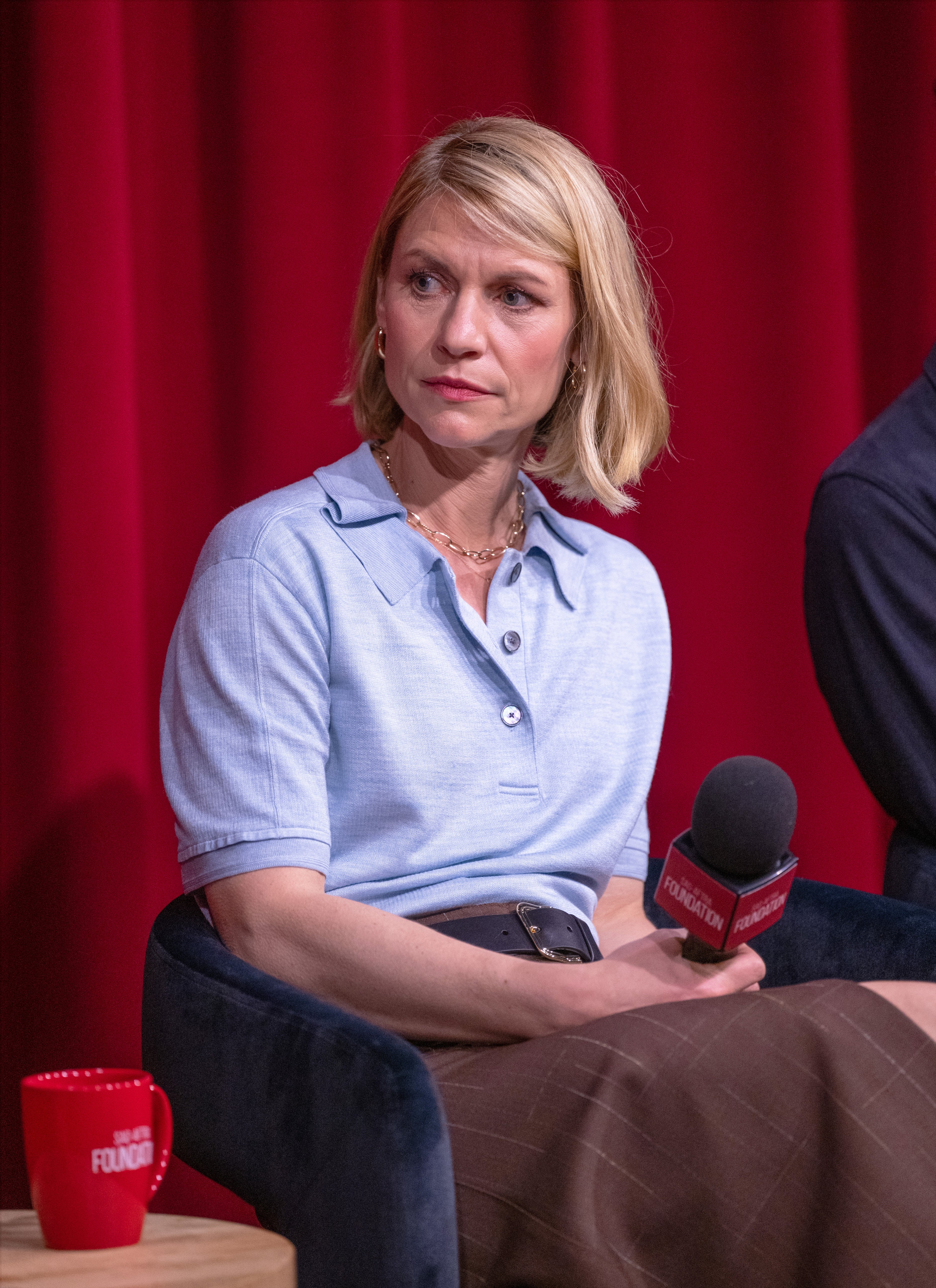 Claire Danes seated on stage holding a microphone